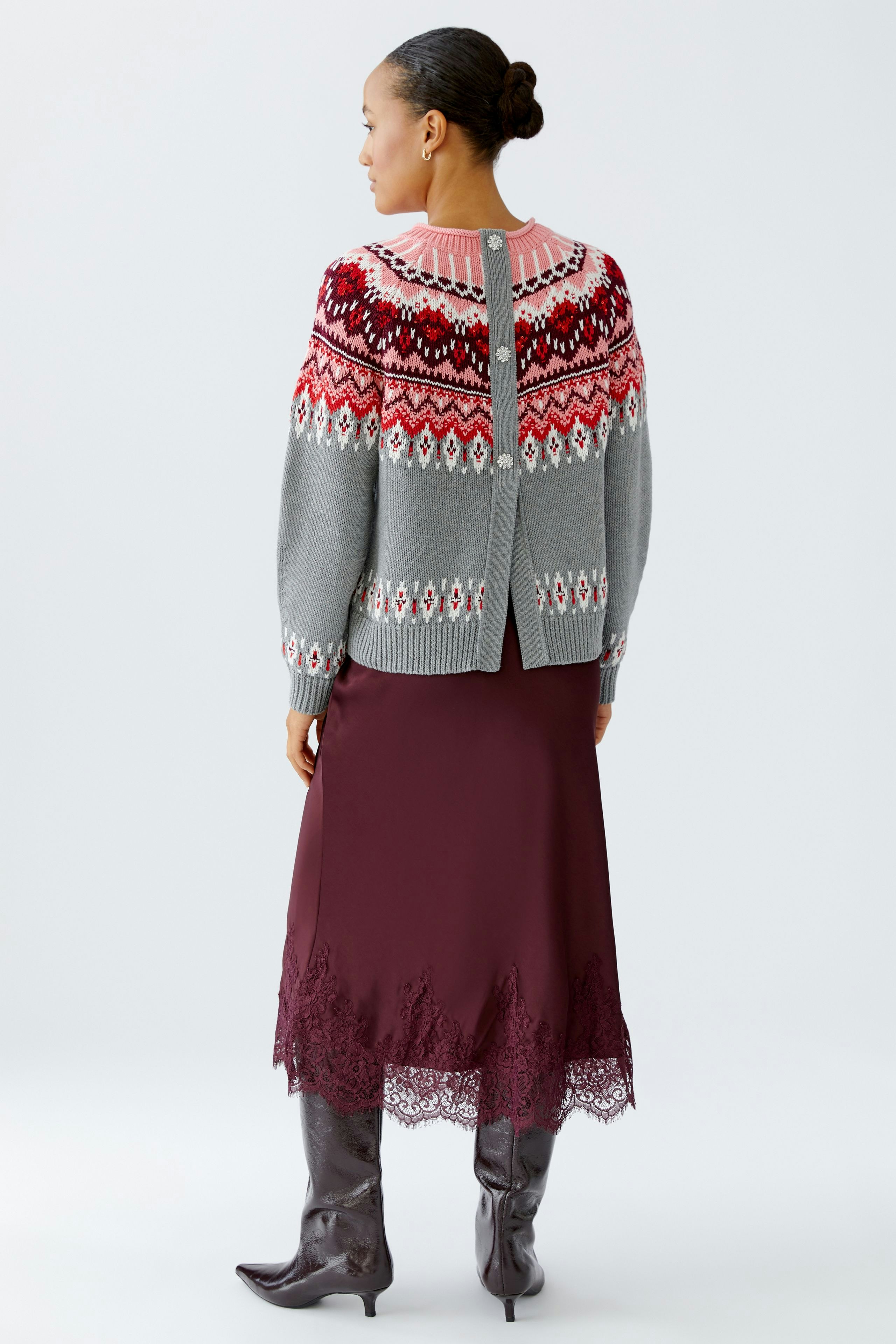 Stylish women's pullover: A woman in a grey patterned pullover with vibrant colors, paired with a long skirt.