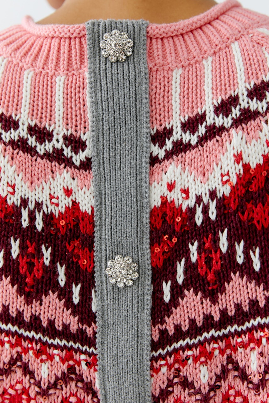 Damen-Pullover: Rückansicht einer Frau in einem bunten Strickpullover mit dekorativen Knöpfen.