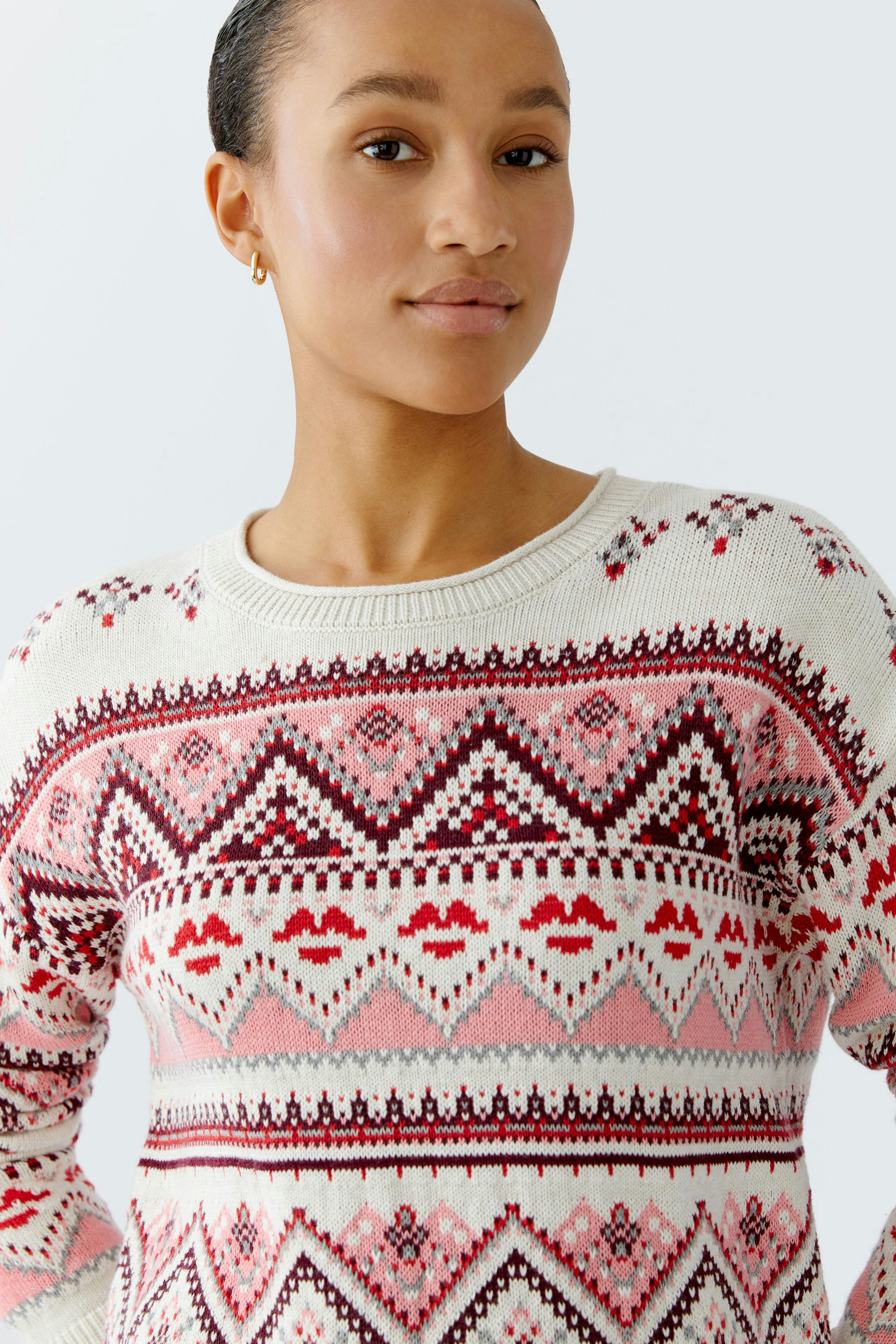 Modern women's pullover: A woman in a cozy patterned pullover with pink and red designs.