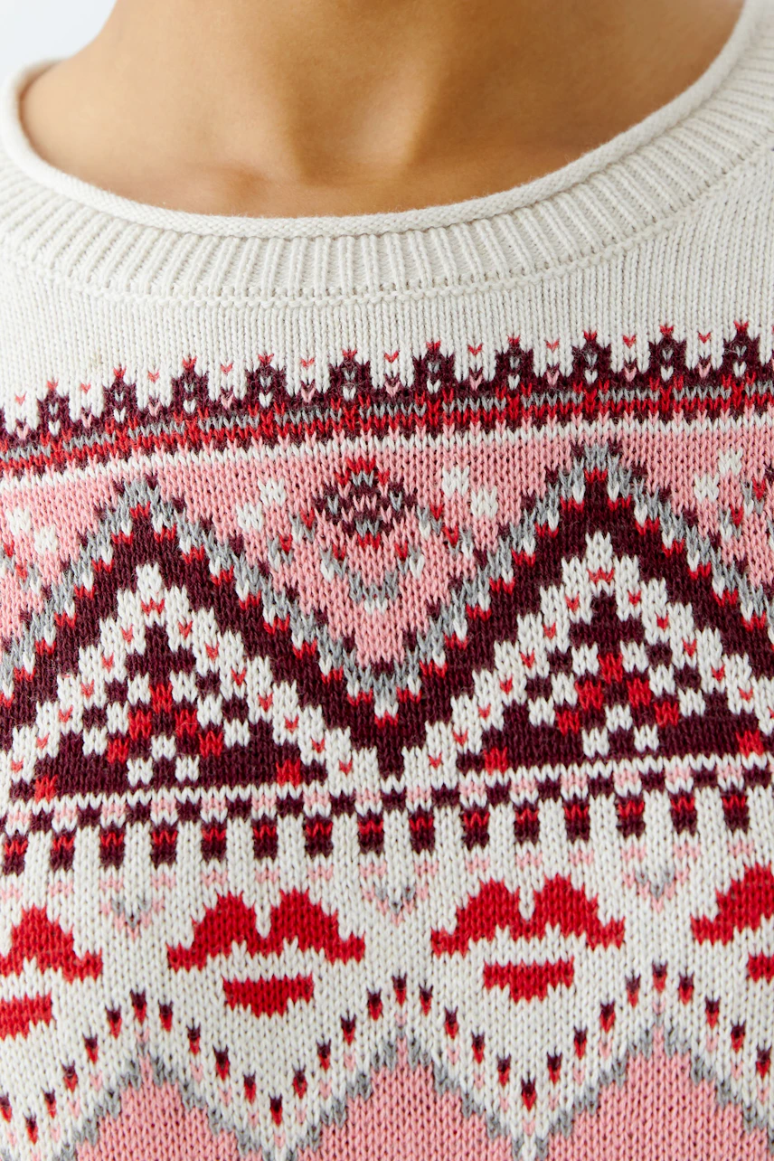 Gemusterter Damen-Pullover: Nahaufnahme eines hellen Pullovers mit buntem, geometrischem Muster.