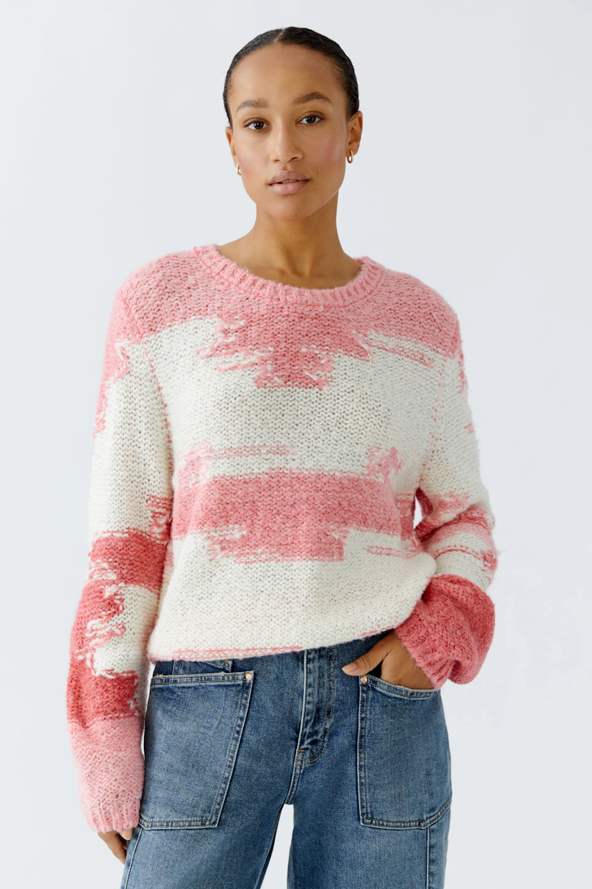 Damen-Pullover: Frau trägt einen lässigen, gestreiften Pullover in Rosa- und Weißtönen.