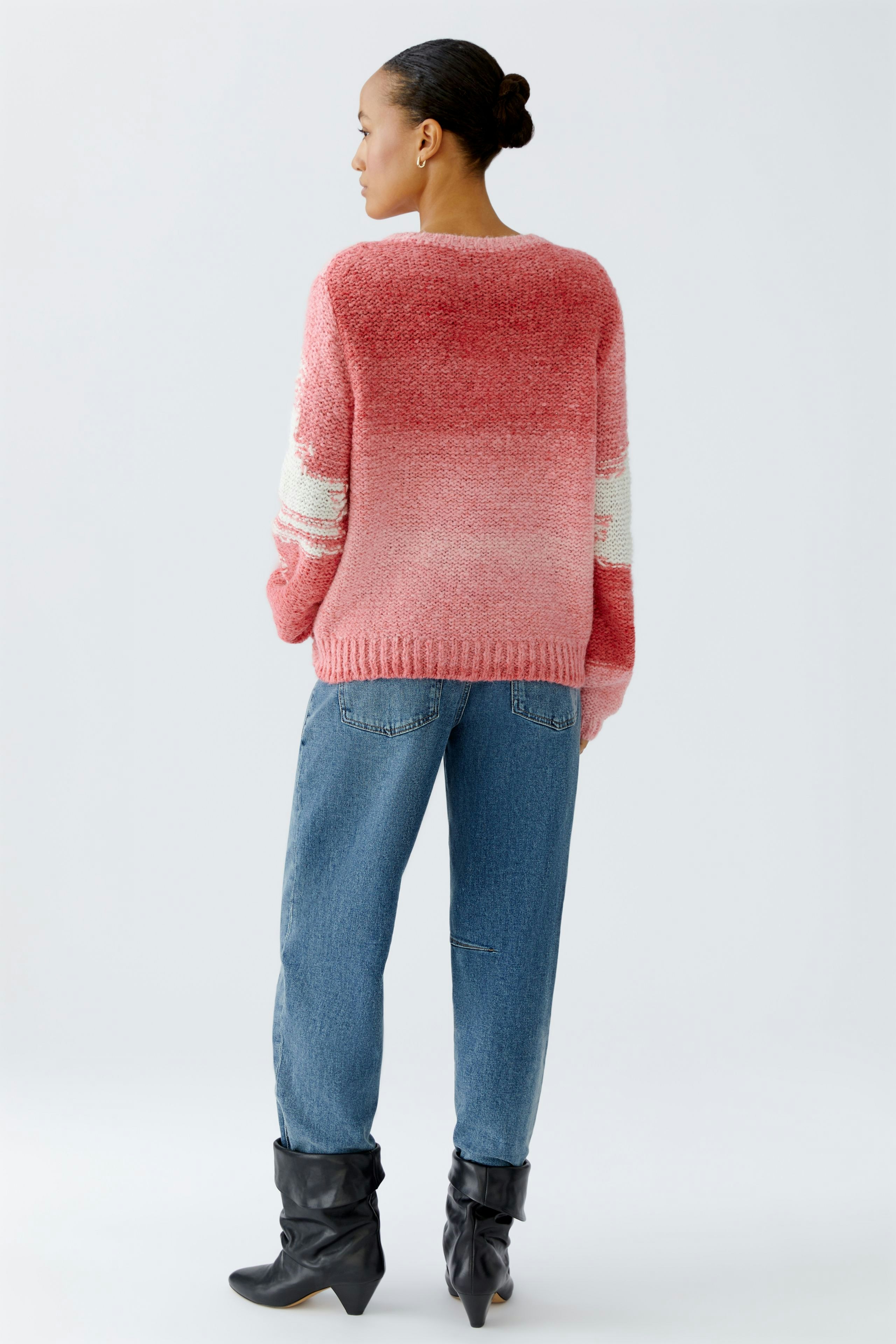 Damen-Pullover: Frau in rosafarbenem, lässigem Strickpullover mit farbigen Akzenten und Jeans.