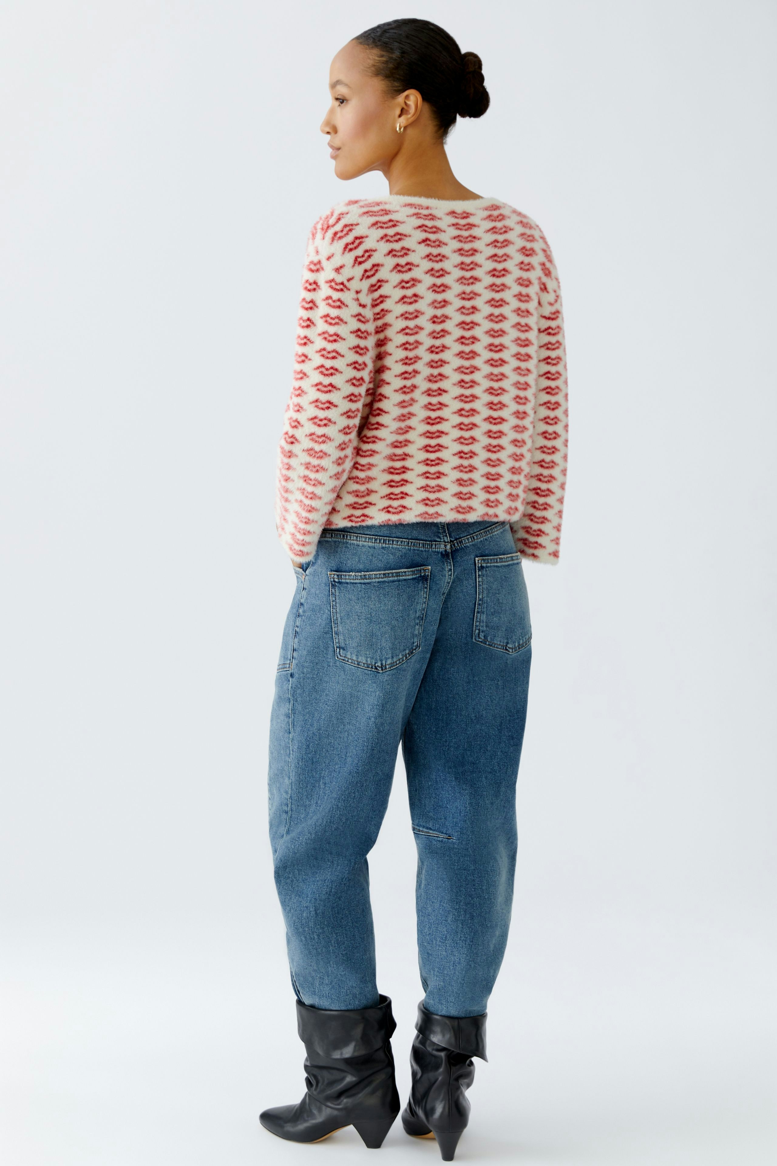 Casual women's pullover: A woman in a patterned pullover and relaxed jeans stands confidently.