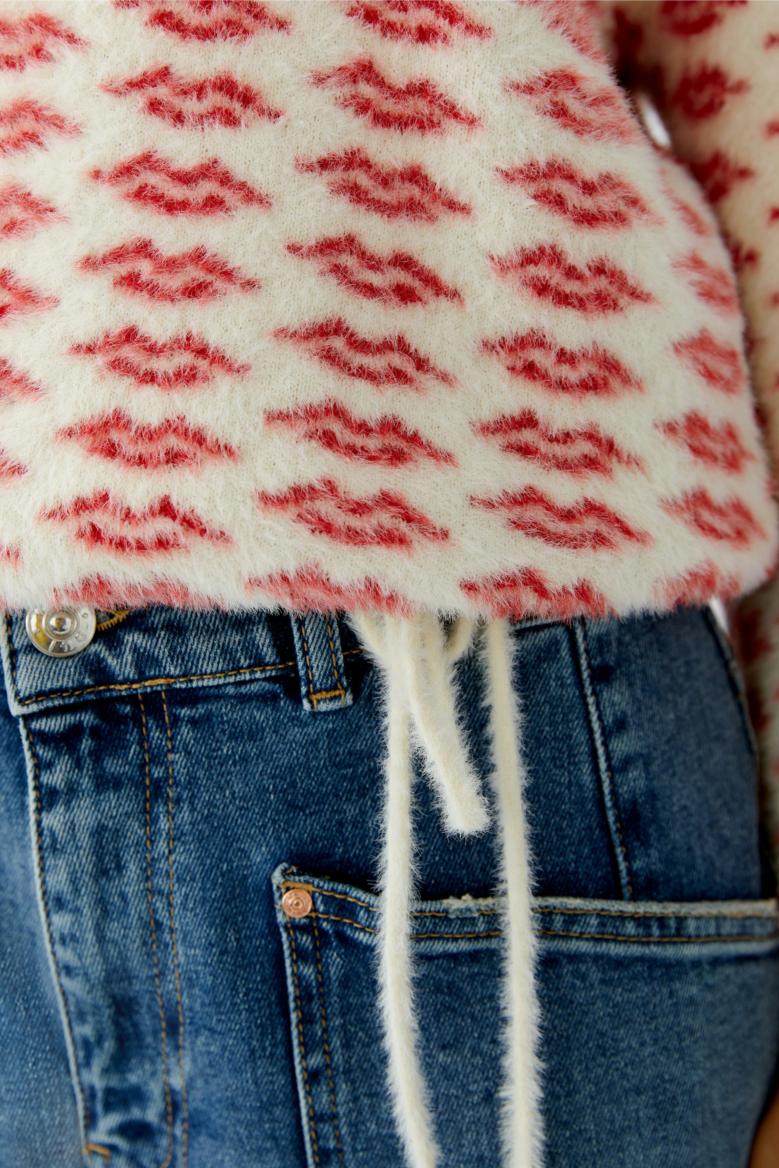Cozy women's pullover with a playful red pattern, paired with casual denim.