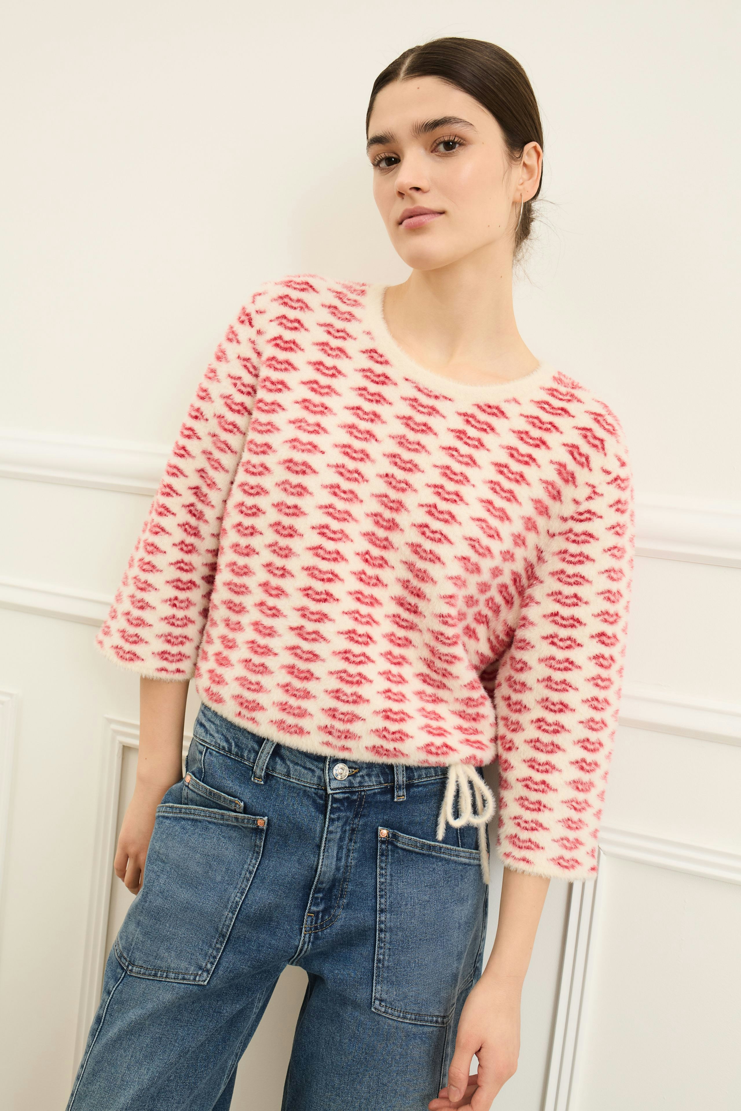 Casual women's pullover: Young woman in a pink patterned pullover with a relaxed fit and drawstring detail.