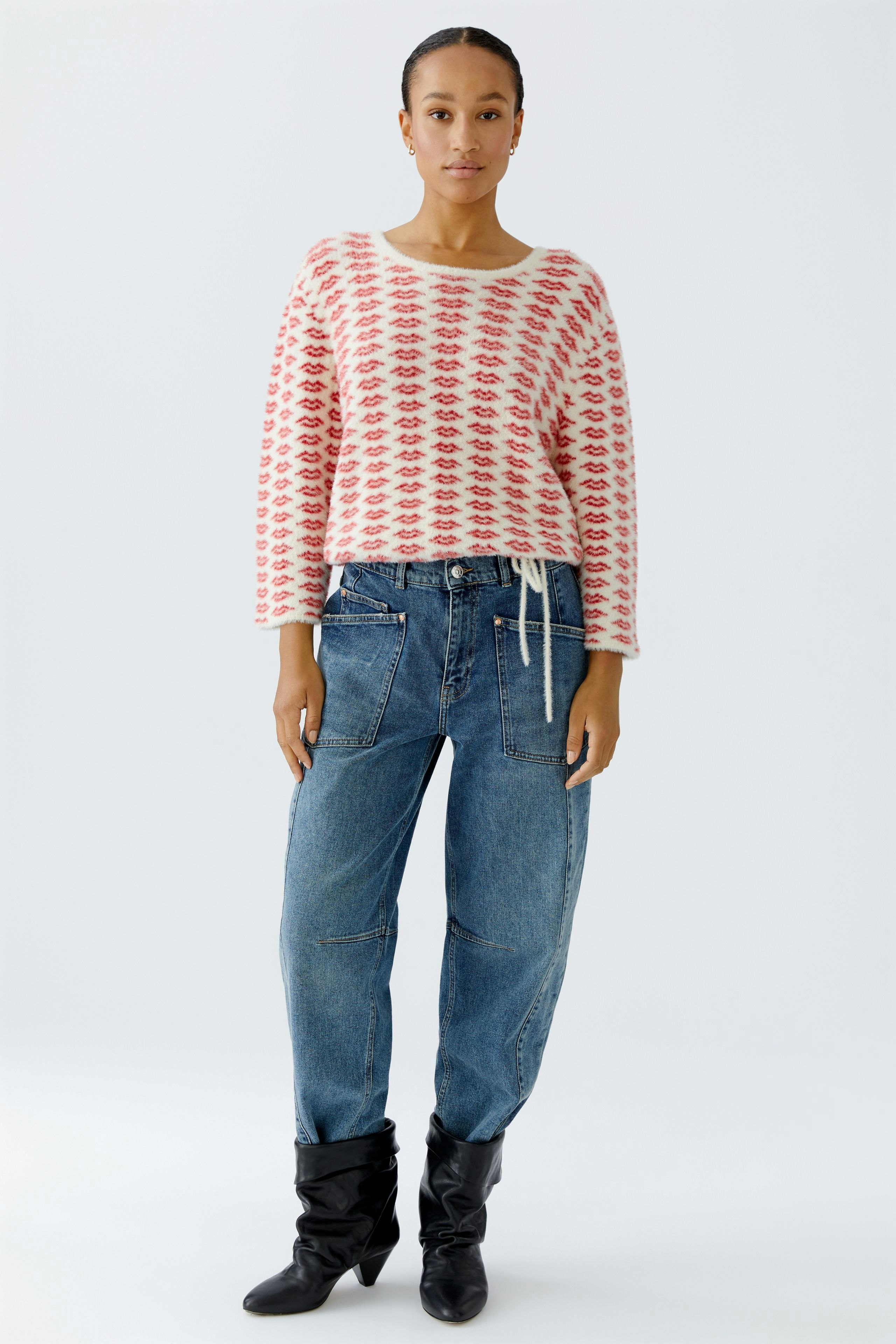 Casual women's pullover: A woman in a pink patterned pullover paired with relaxed-fit jeans.