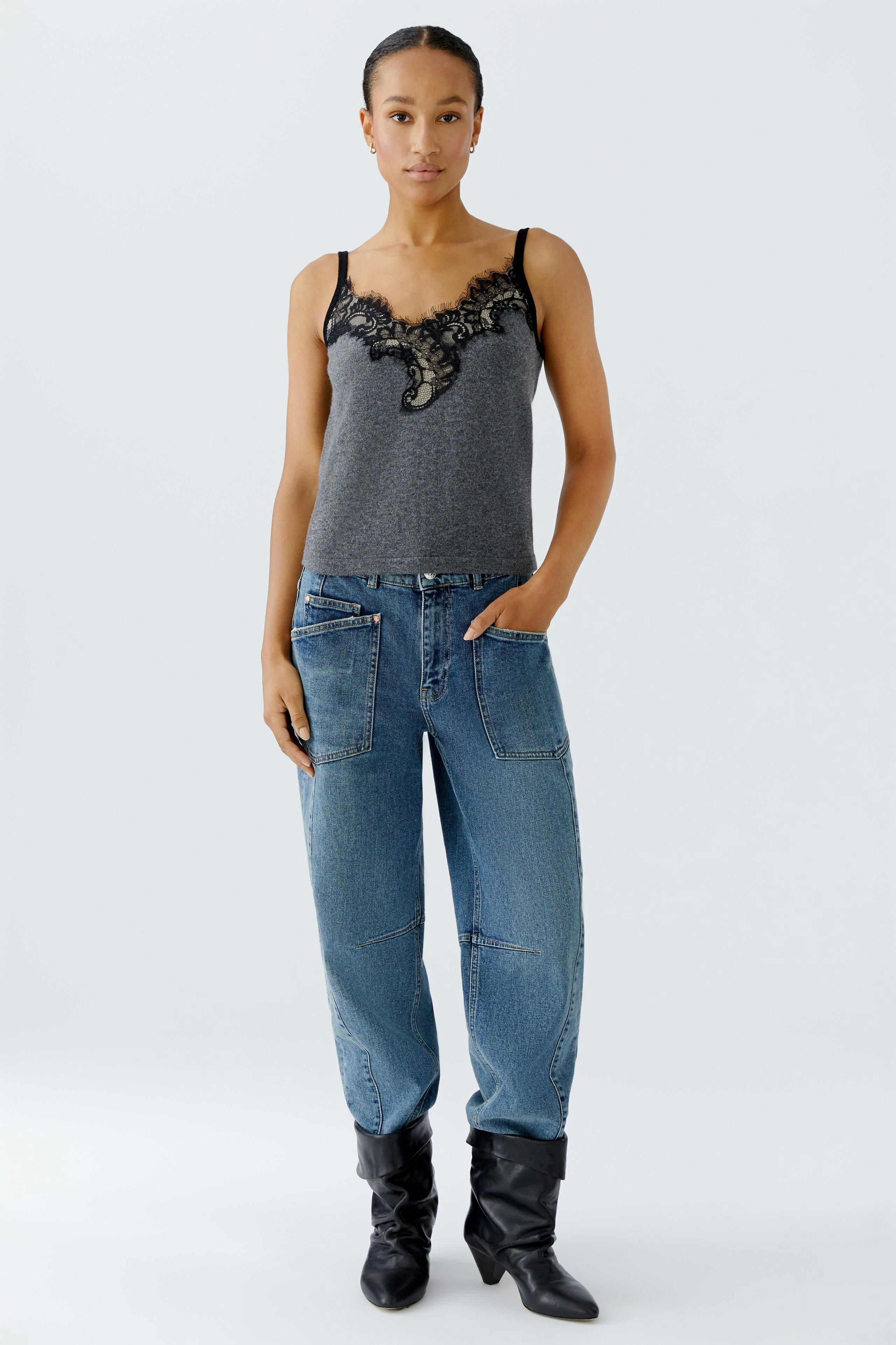 Casual women's top: A woman in a gray tank top with lace detailing, paired with relaxed jeans.