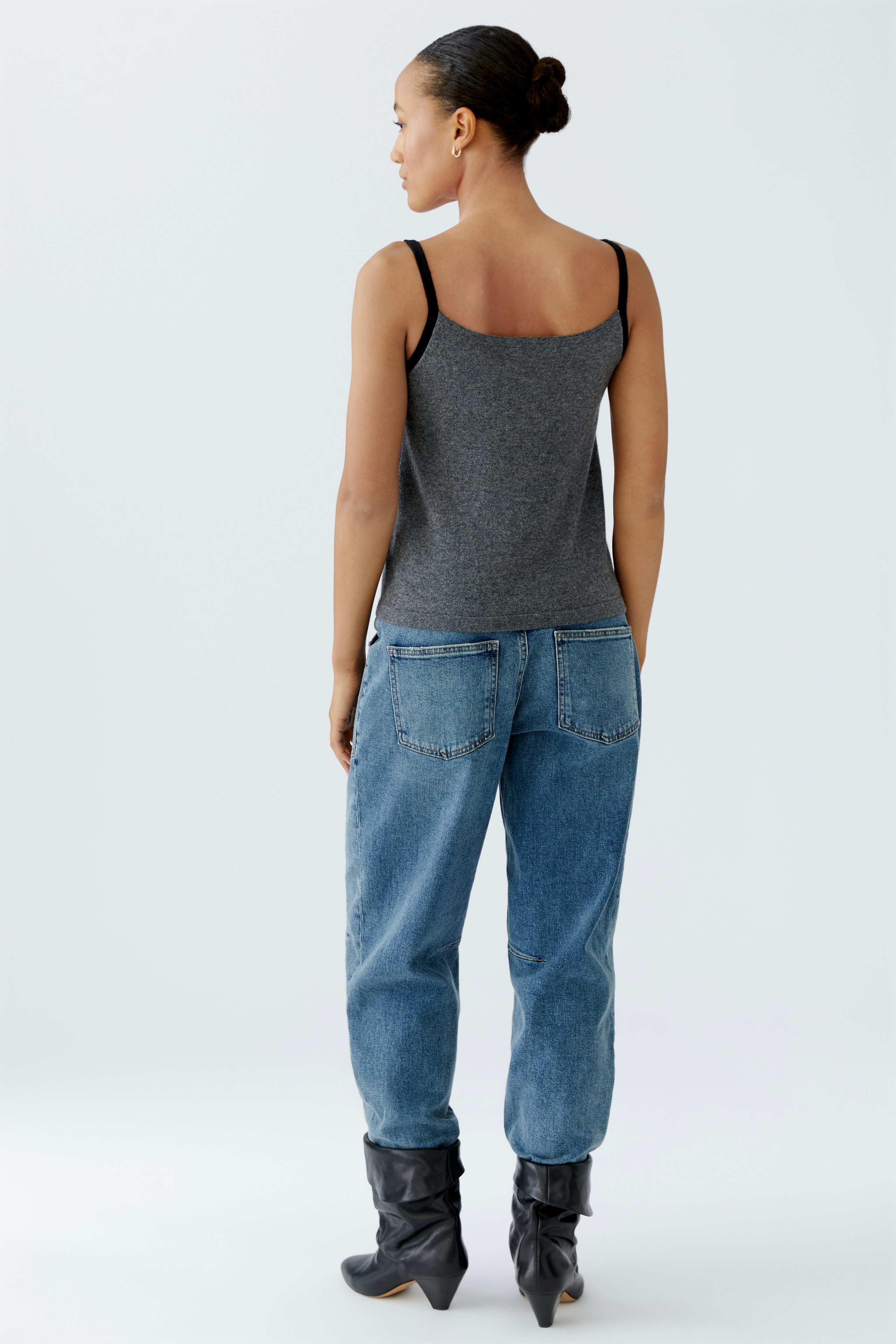 Casual women's top: Young woman in a gray tank top paired with relaxed-fit jeans.