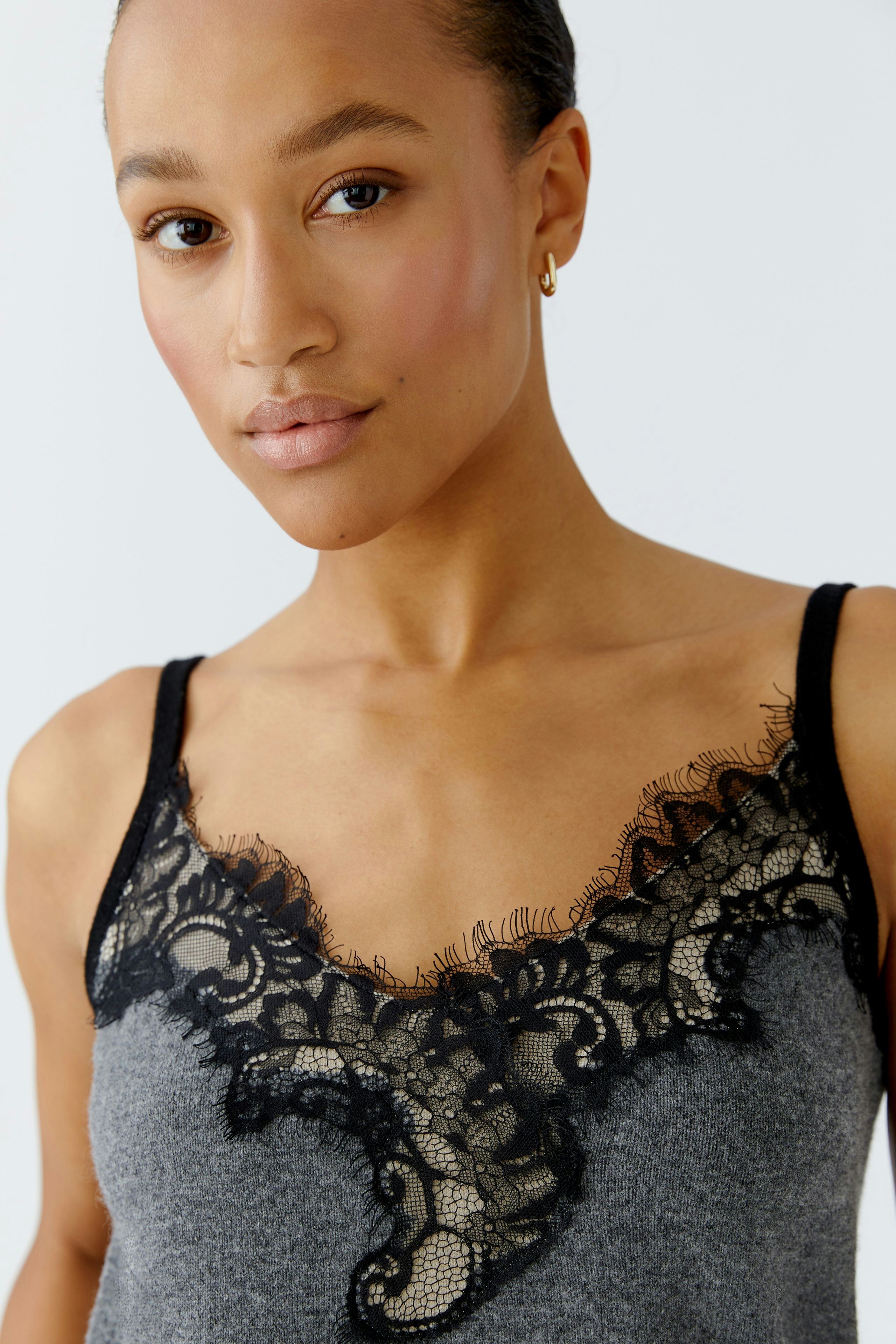 Stylish women's top: A woman in a gray top with black lace detailing, showcasing a casual look.