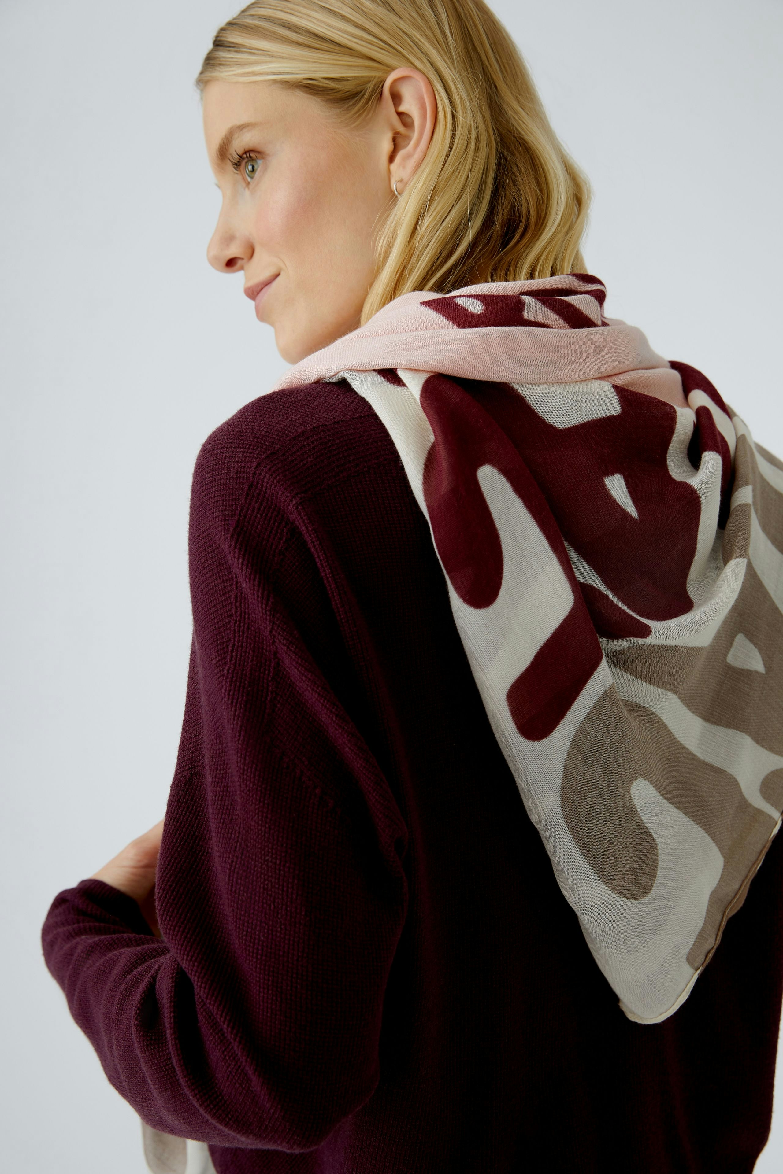 Casual women's pullover: Woman wearing a maroon pullover with a patterned scarf draped over her shoulder.