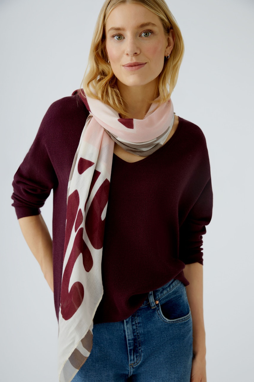Damen-Pullover in dunkellila, kombiniert mit einem leichten, gemusterten Schal. Junge Frau trägt lässigen Look.