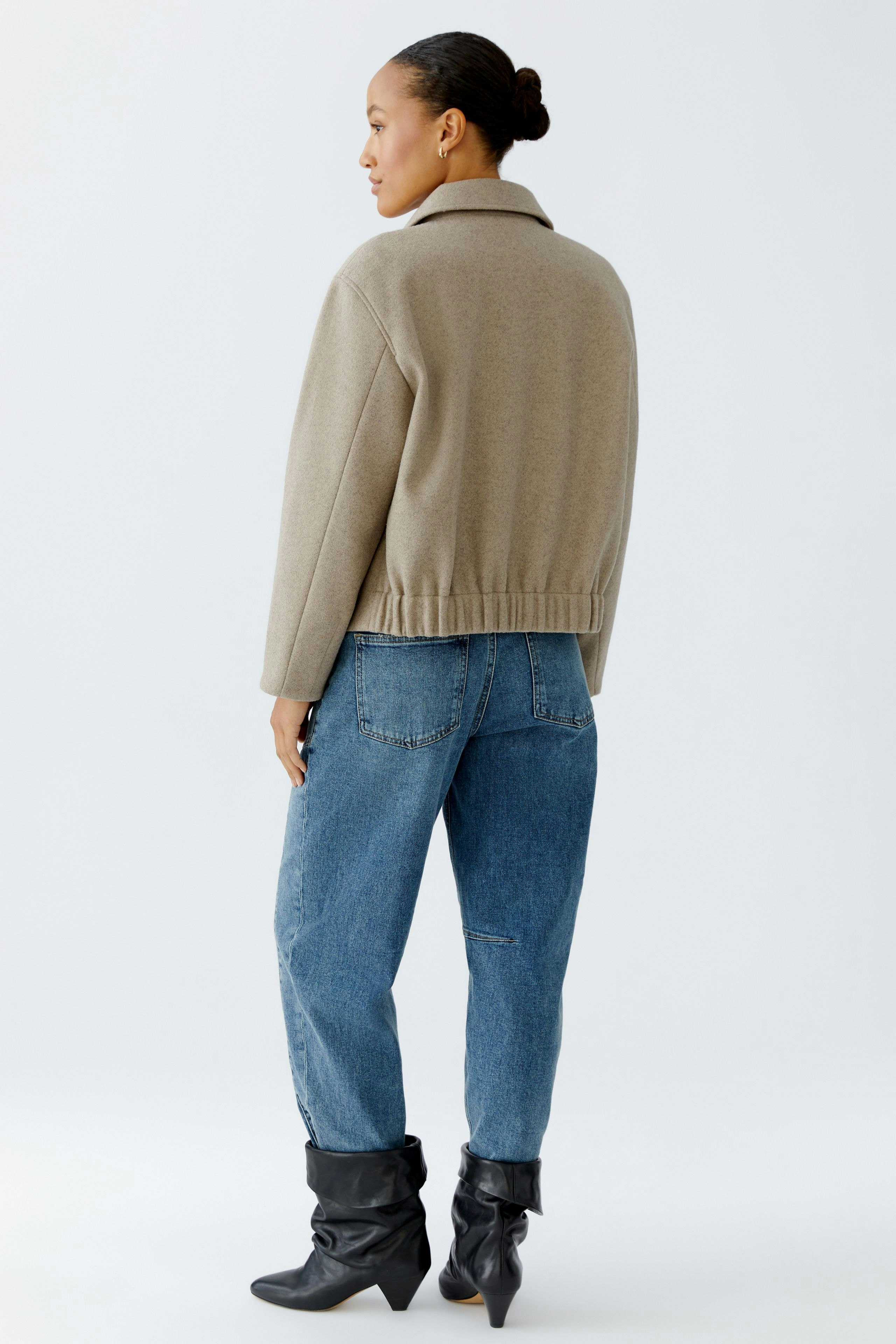 Bequeme Damen-Jacke: Frau in beiger Jacke mit lässigem Schnitt und Jeans, von hinten zu sehen.