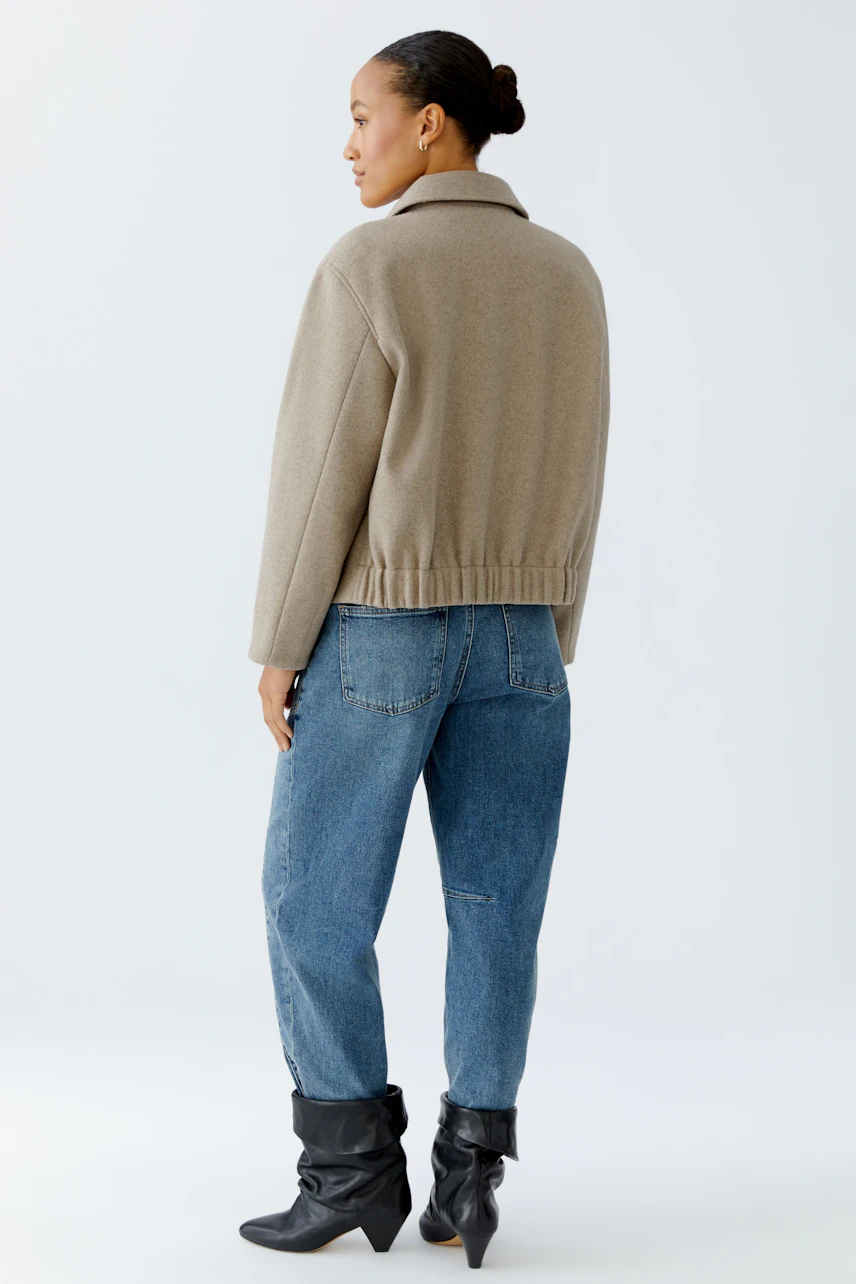 Casual women's jacket: A woman in a beige jacket paired with blue jeans, showcasing a relaxed style.