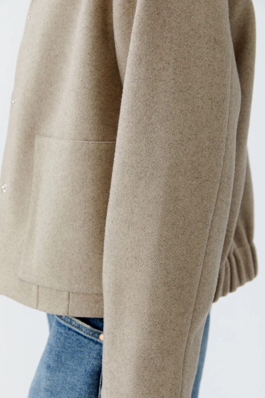 Casual women's jacket: A woman in a beige jacket with a relaxed fit and side pockets.