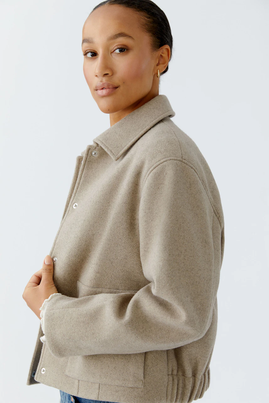 Casual women's jacket: A woman in a beige jacket with a collar, showcasing a relaxed style.