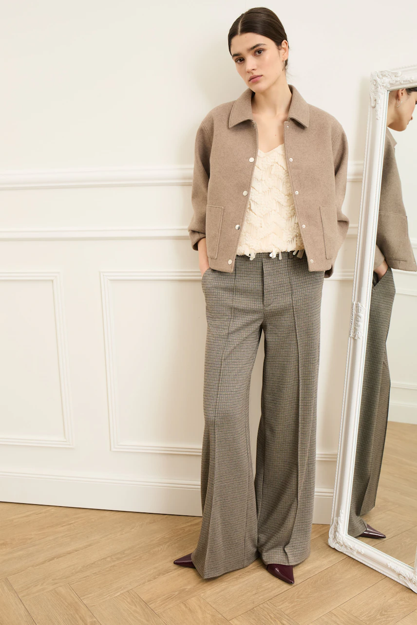 Casual women's jacket: Young woman in a beige jacket over a light top, paired with wide trousers.