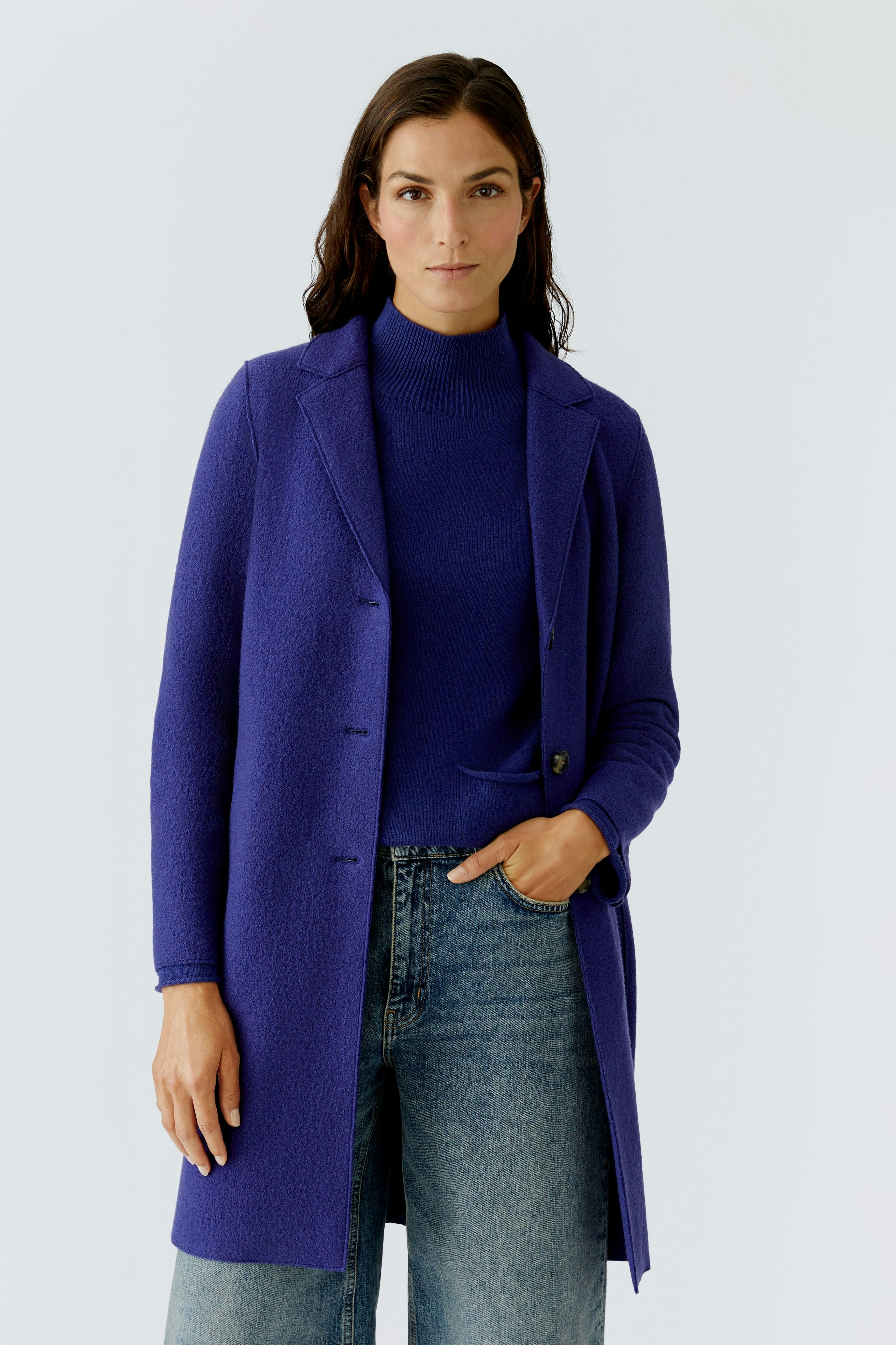 Wool coat: Woman in a vibrant purple wool coat over a striped pullover and brown pants.