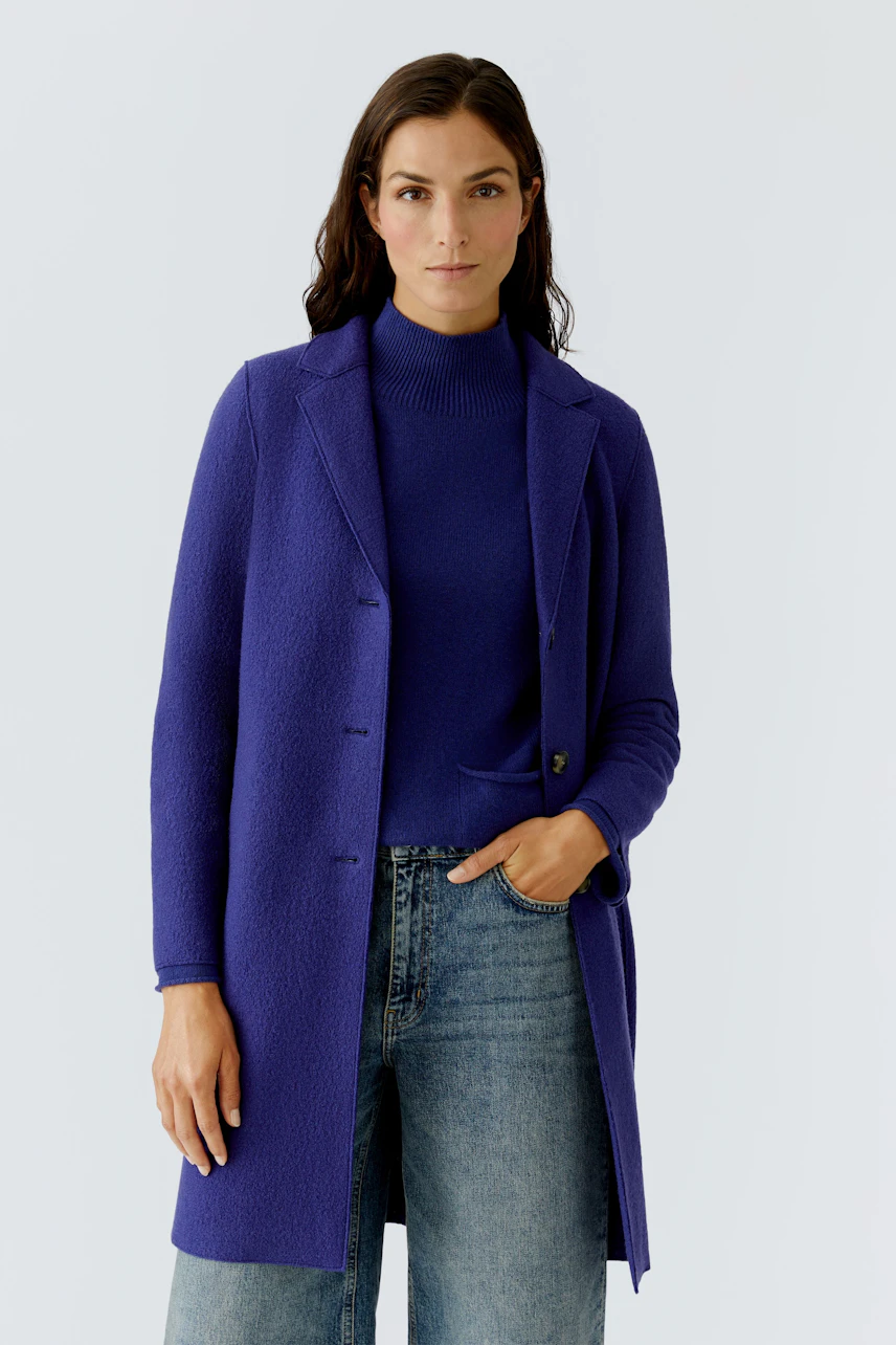 Wool coat: Woman in a vibrant purple wool coat over a striped pullover and brown pants.