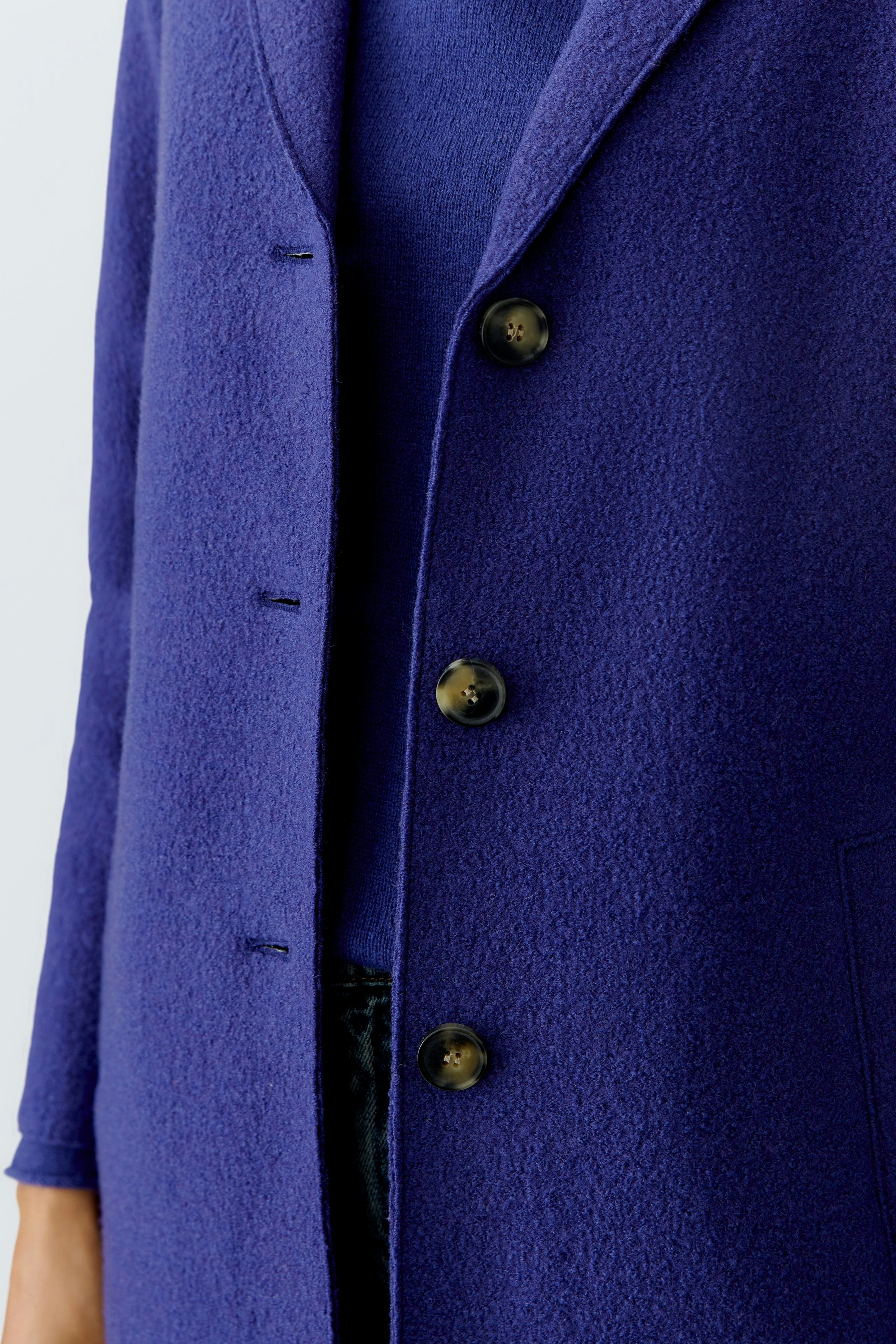 Wool coat: Woman wearing a vibrant purple wool coat with a relaxed fit and button details.