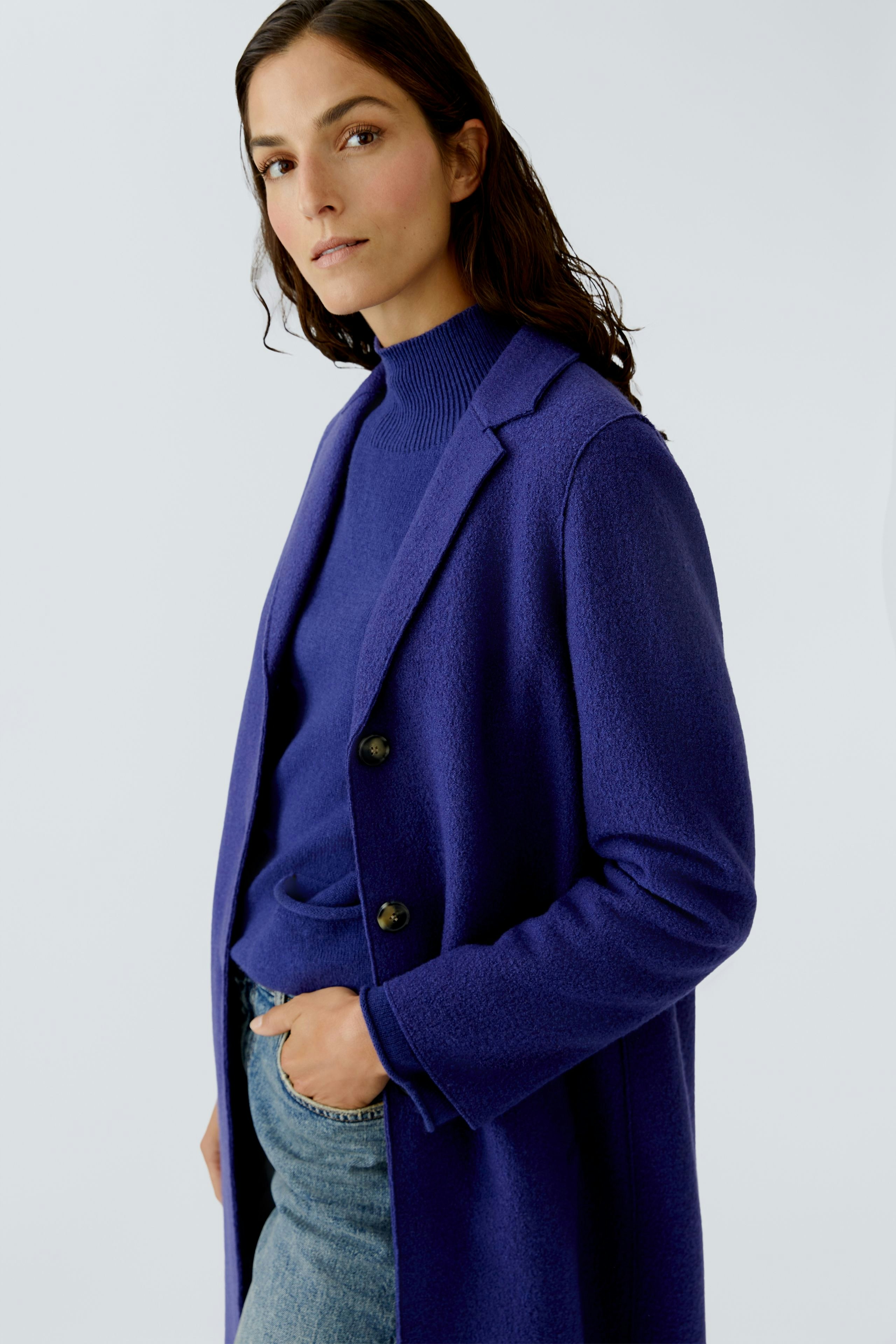Stylish women's wool coat in vibrant blue, paired with a matching pullover and casual jeans.