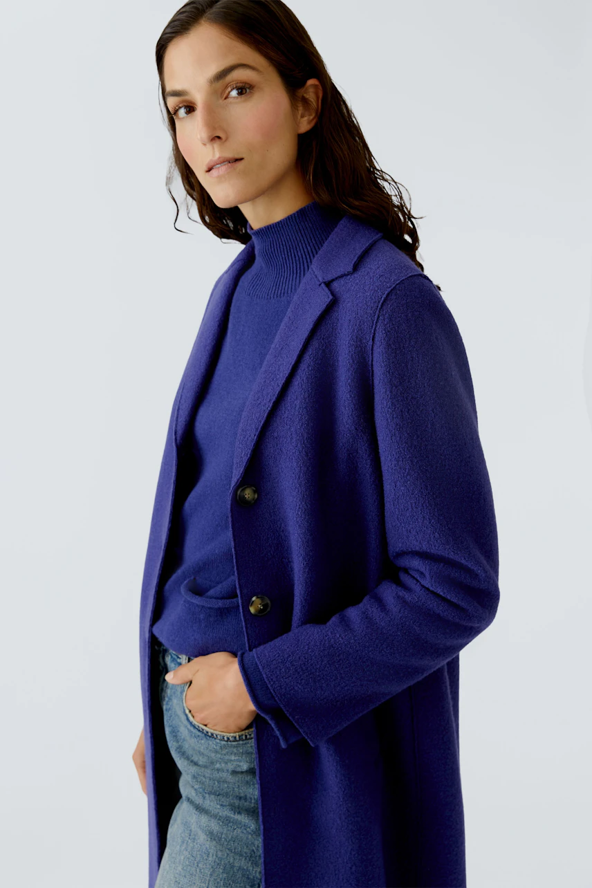 Stylish women's wool coat in vibrant blue, paired with a matching pullover and casual jeans.