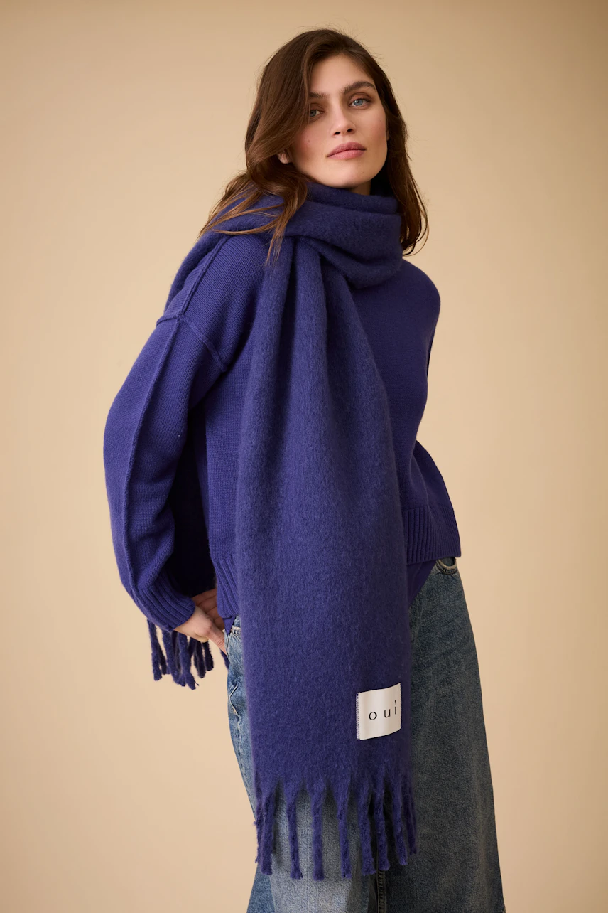 Cozy women's scarf in deep purple, styled with a relaxed pullover and casual jeans.