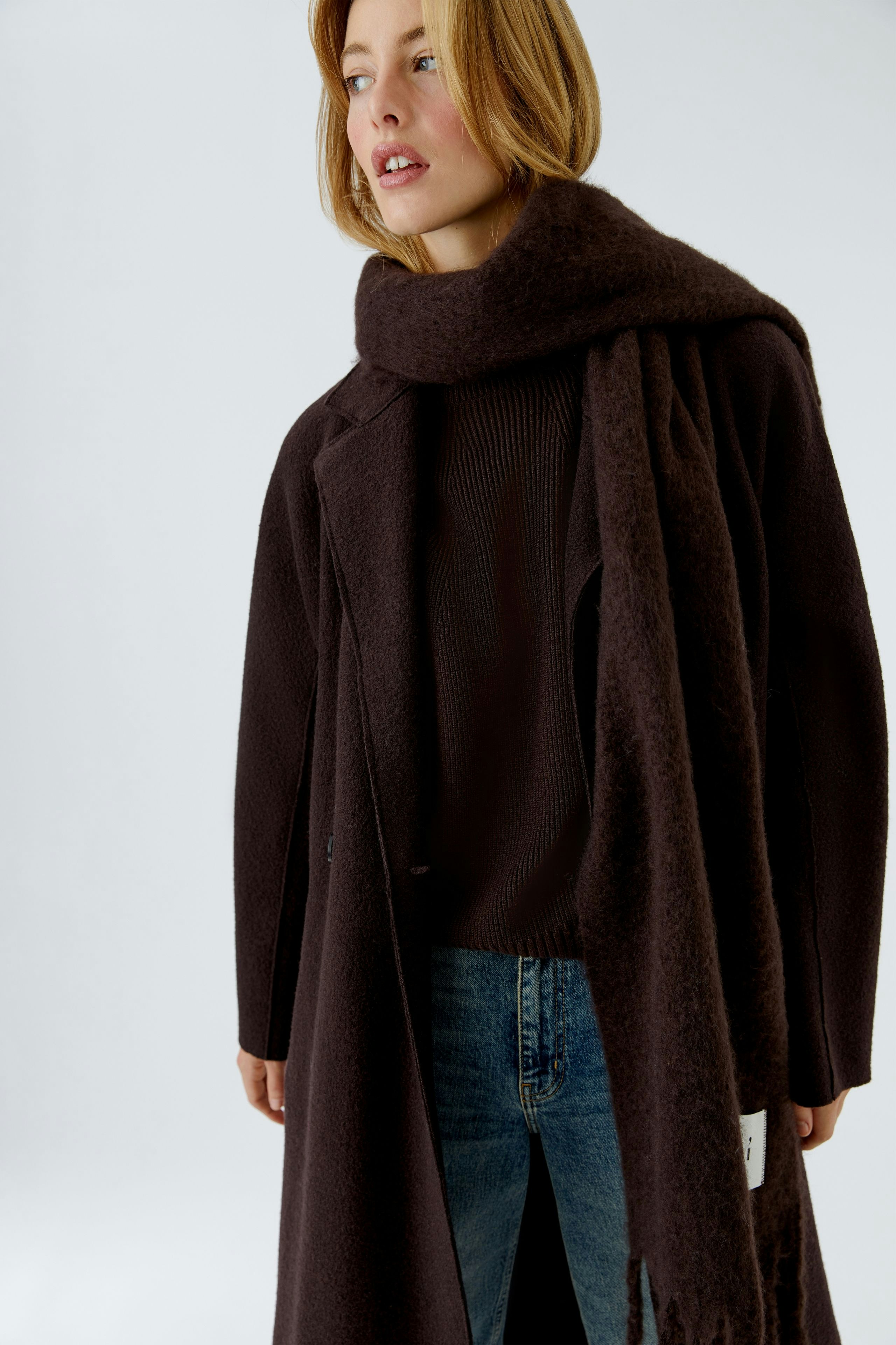 Cozy women's scarf in dark brown, styled with a matching coat and casual jeans.
