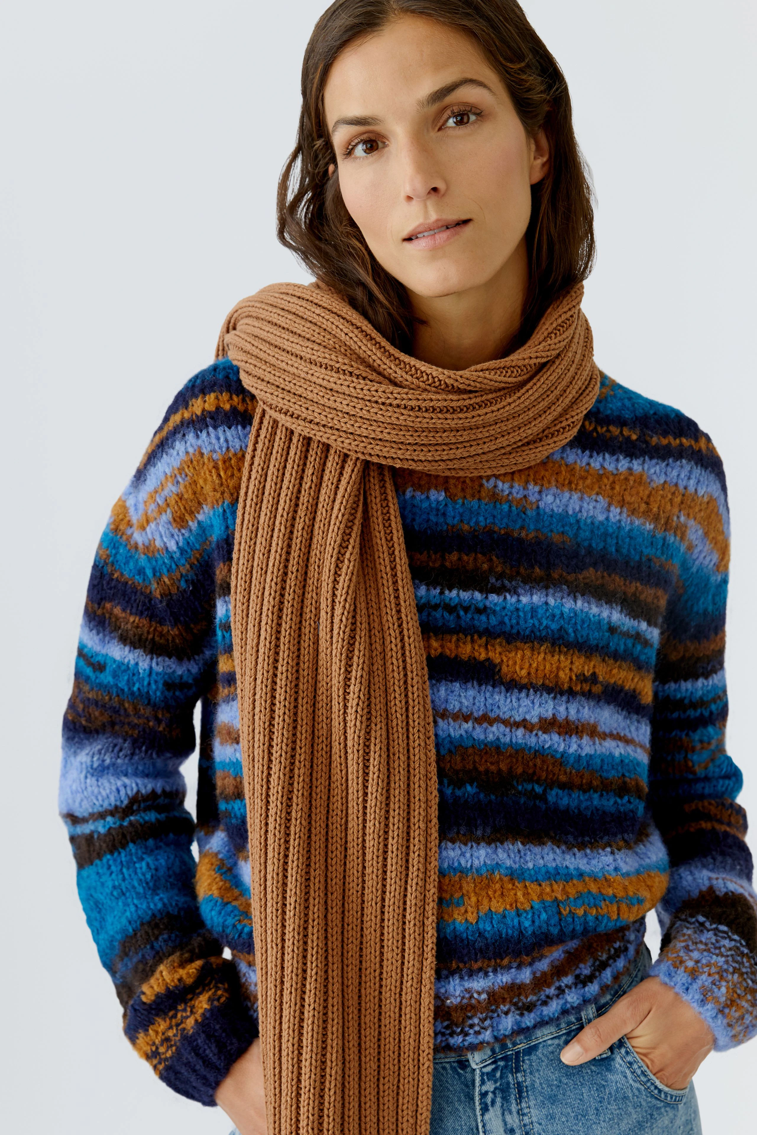 Damen-Schal in warmen Brauntönen, lässig um den Hals drapiert, kombiniert mit einem bunten Pullover.
