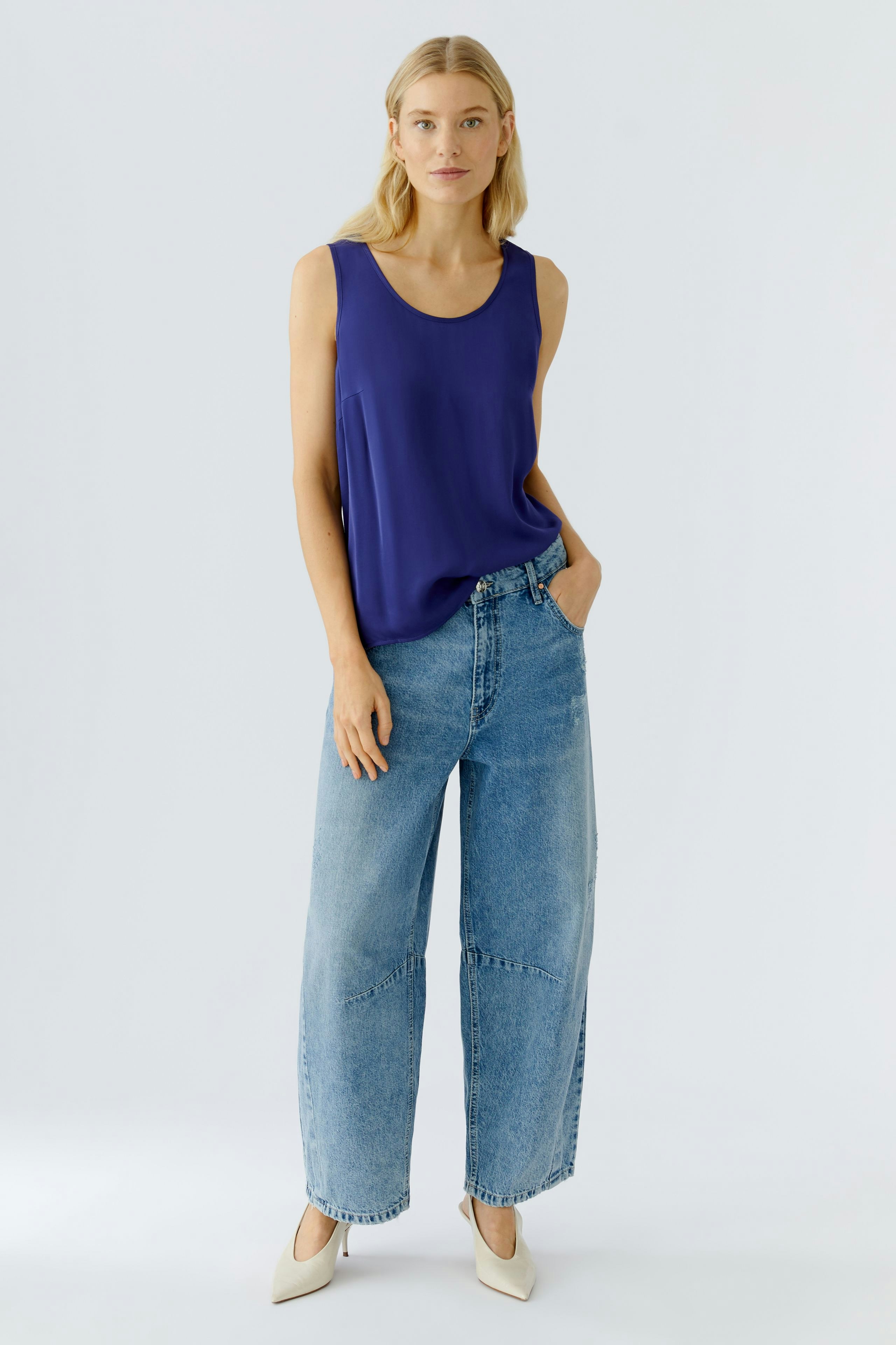 Casual women's top: A woman in a purple sleeveless top paired with relaxed-fit jeans.