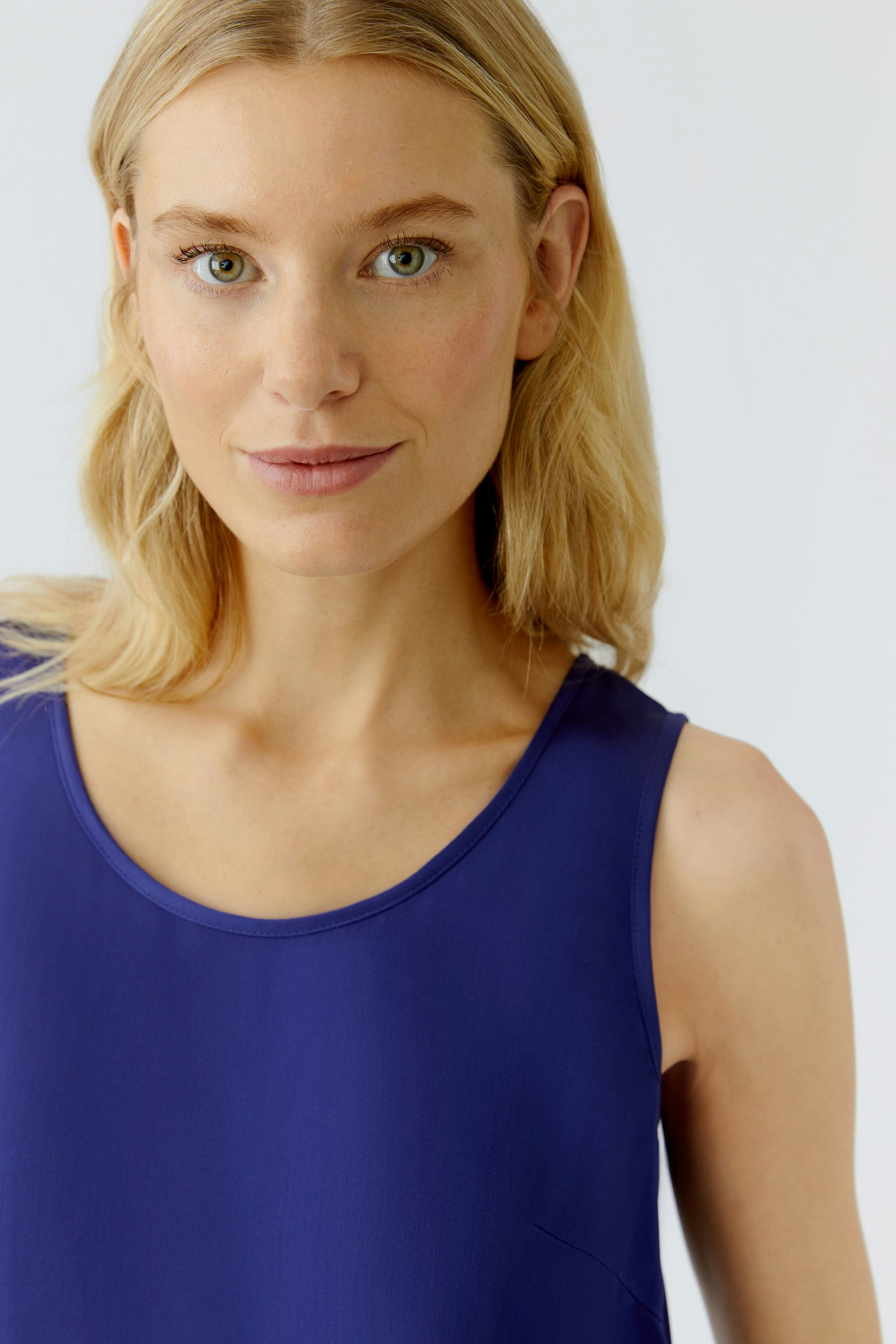 Casual women's top: Young woman in a vibrant blue sleeveless top, showcasing a relaxed style.