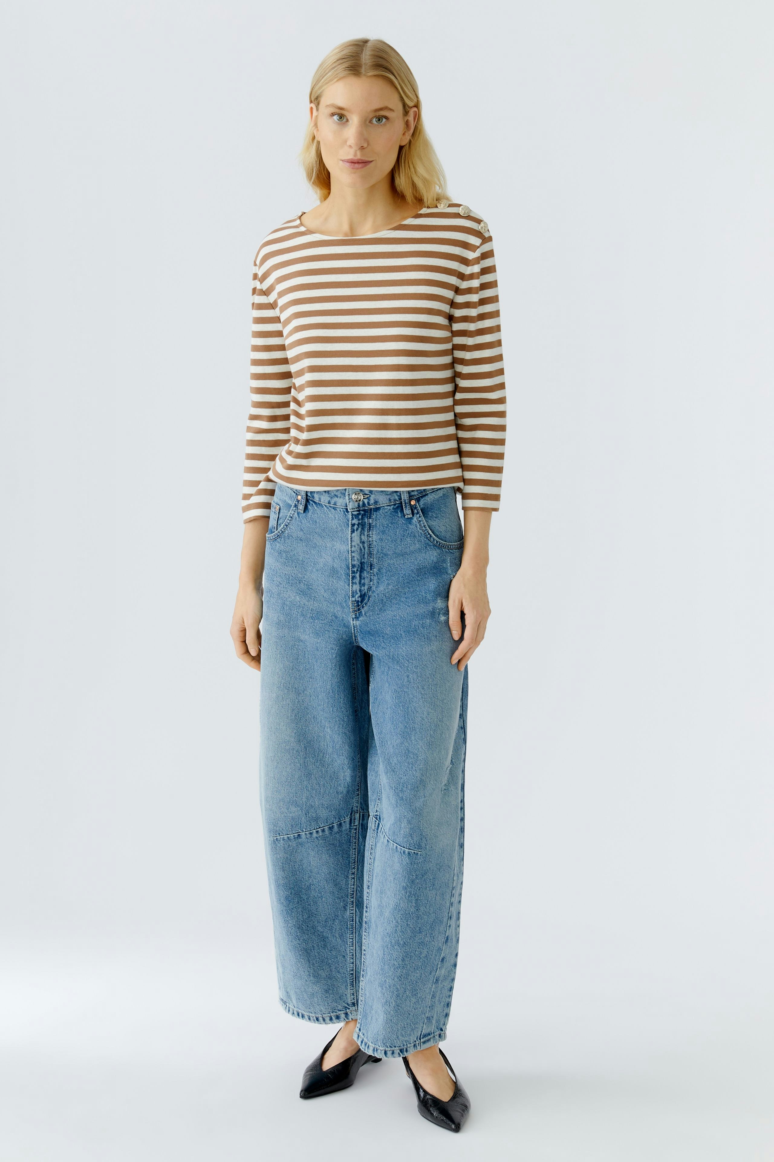 Casual women's long-sleeve shirt: A woman in a striped top and relaxed jeans stands confidently.