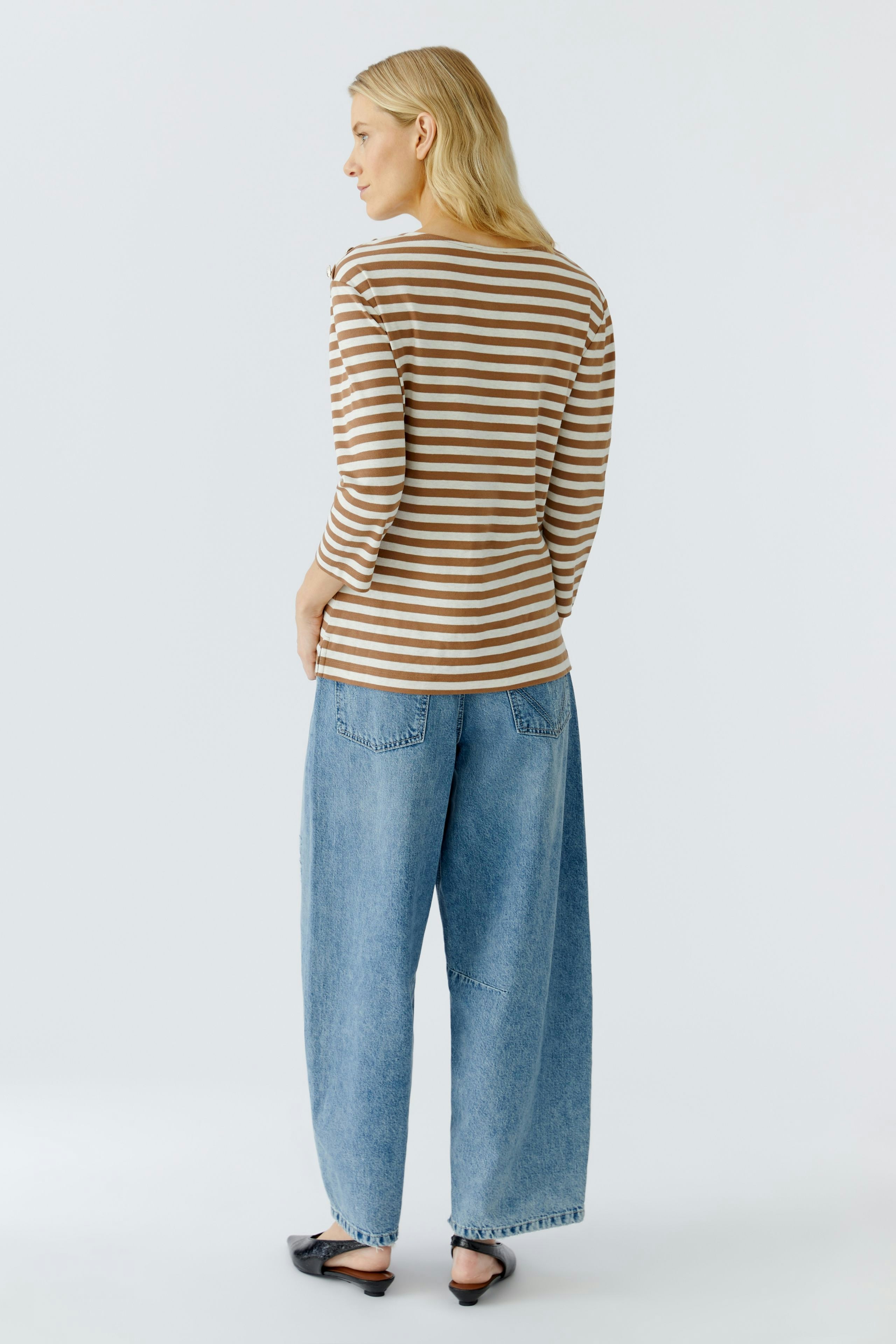 Casual long-sleeve shirt: Woman in a striped pullover with relaxed fit and wide jeans.