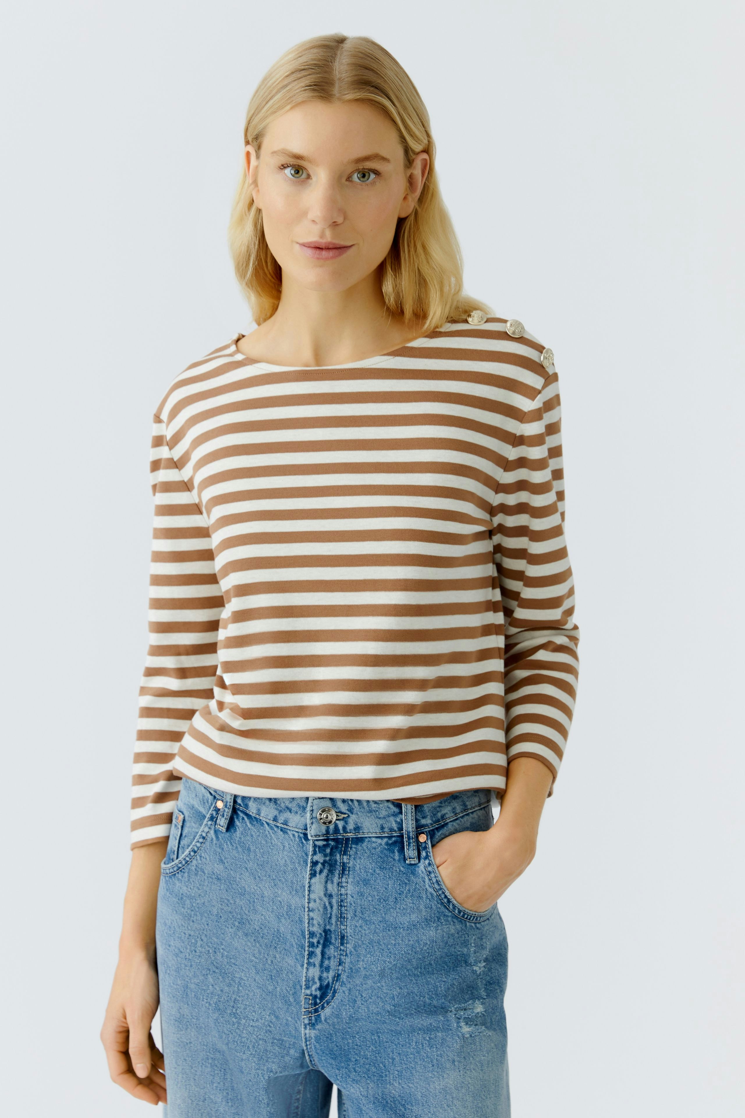 Casual long-sleeve shirt: Woman in a striped pullover with button details, paired with relaxed jeans.
