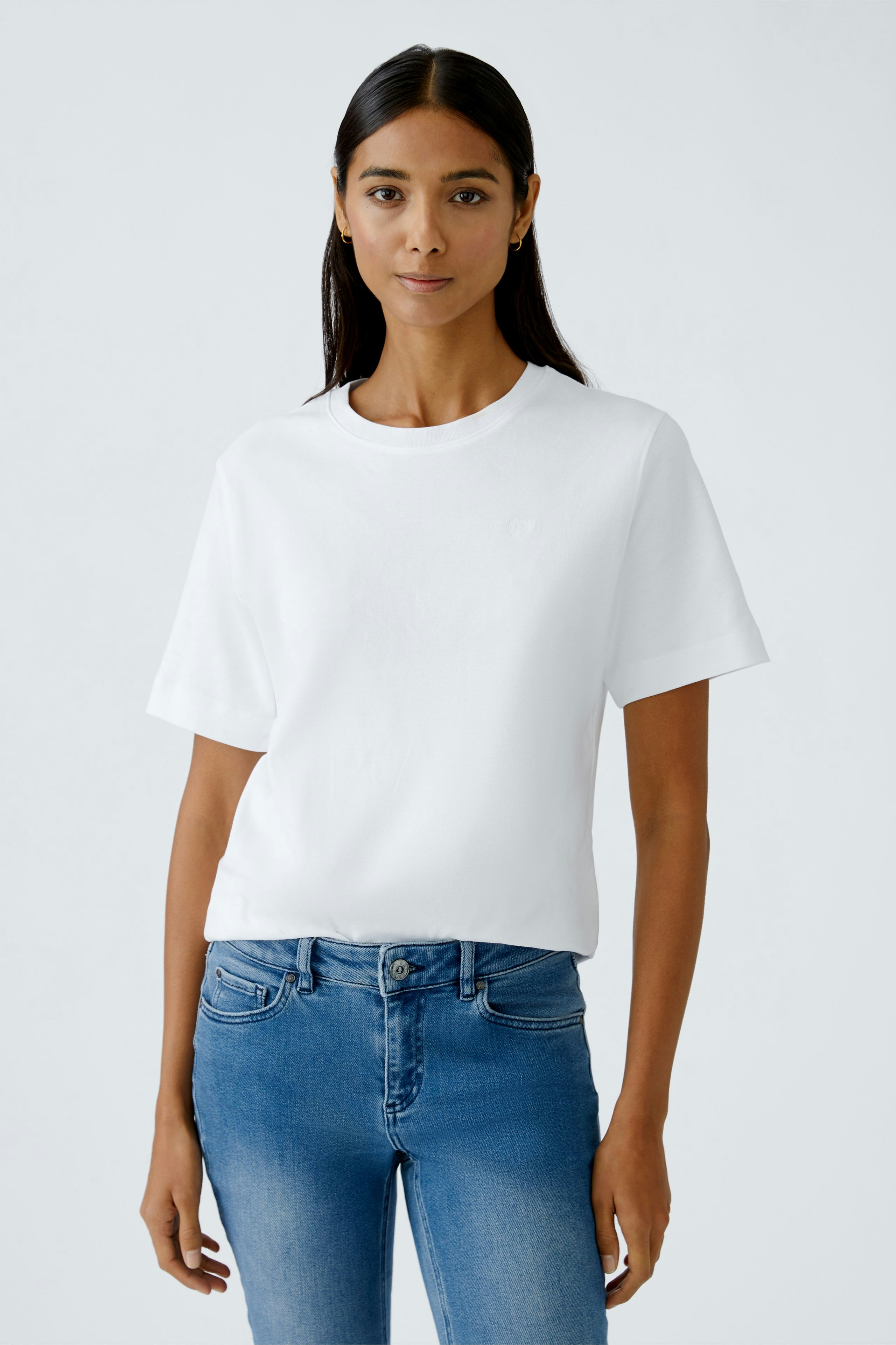 Casual women's T-shirt: Young woman in a white tee paired with blue jeans, exuding a relaxed vibe.