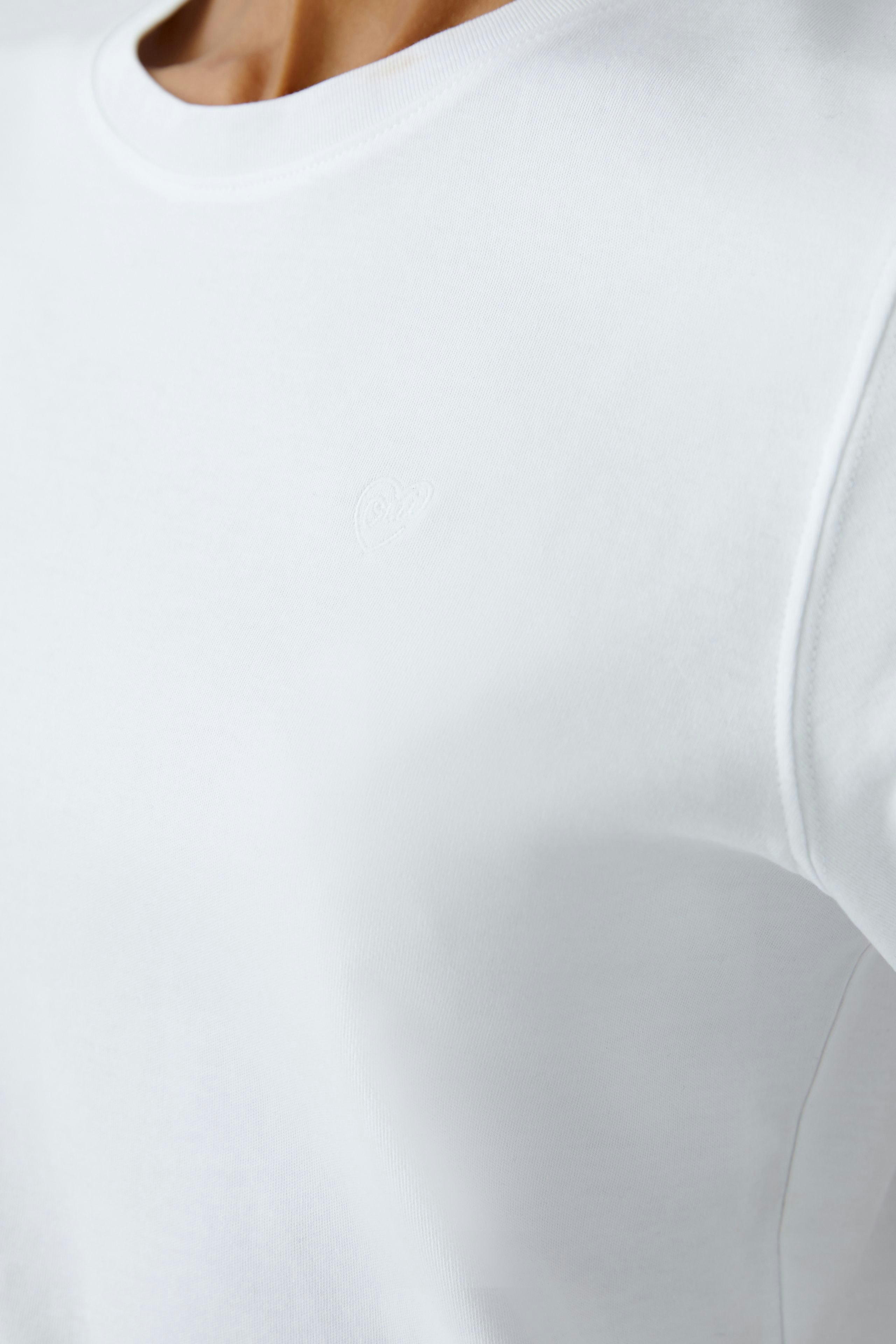 Casual women's T-shirt: Close-up of a woman in a white T-shirt with a subtle logo.