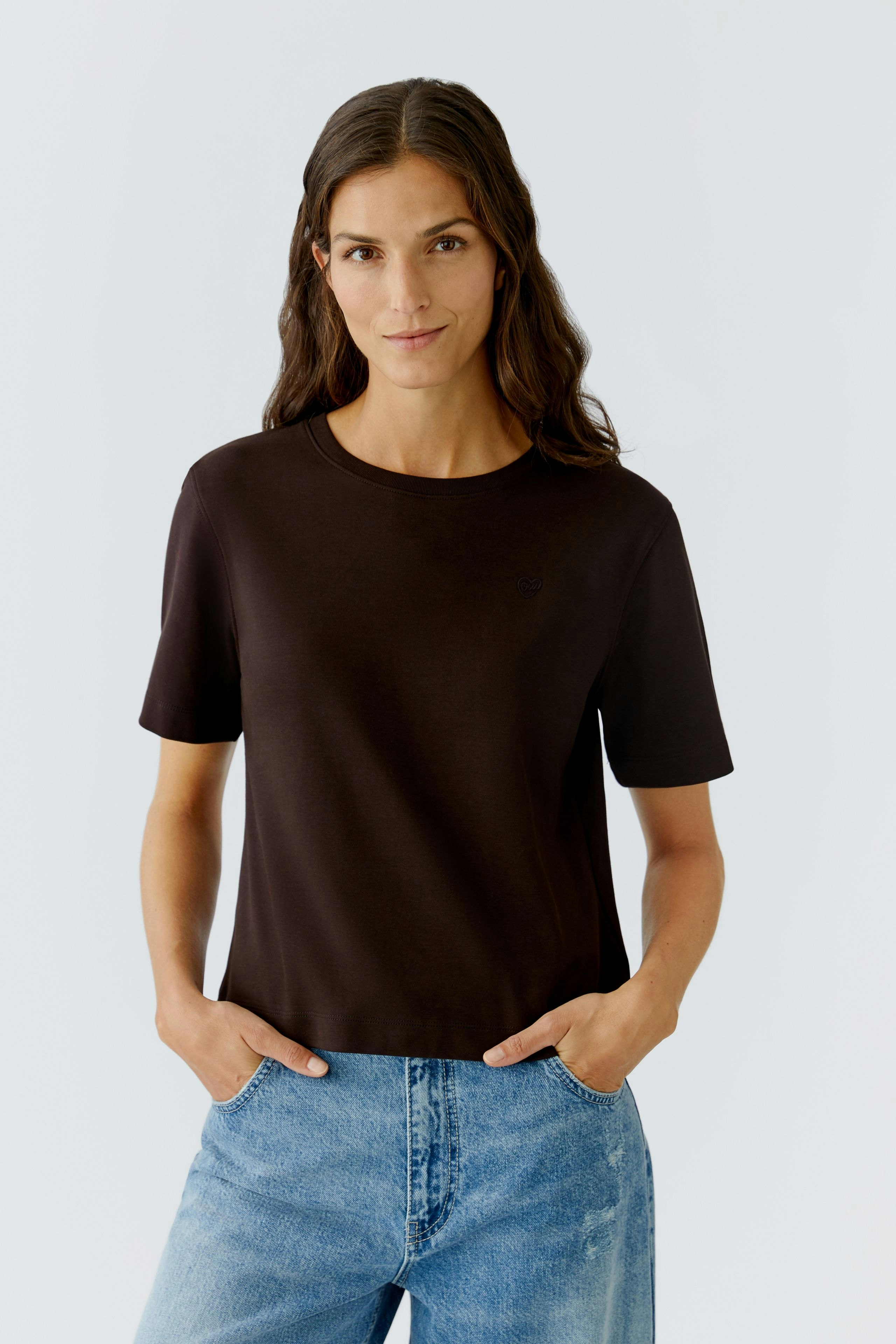 Casual women's T-shirt: A woman in a black short-sleeve T-shirt paired with blue jeans.