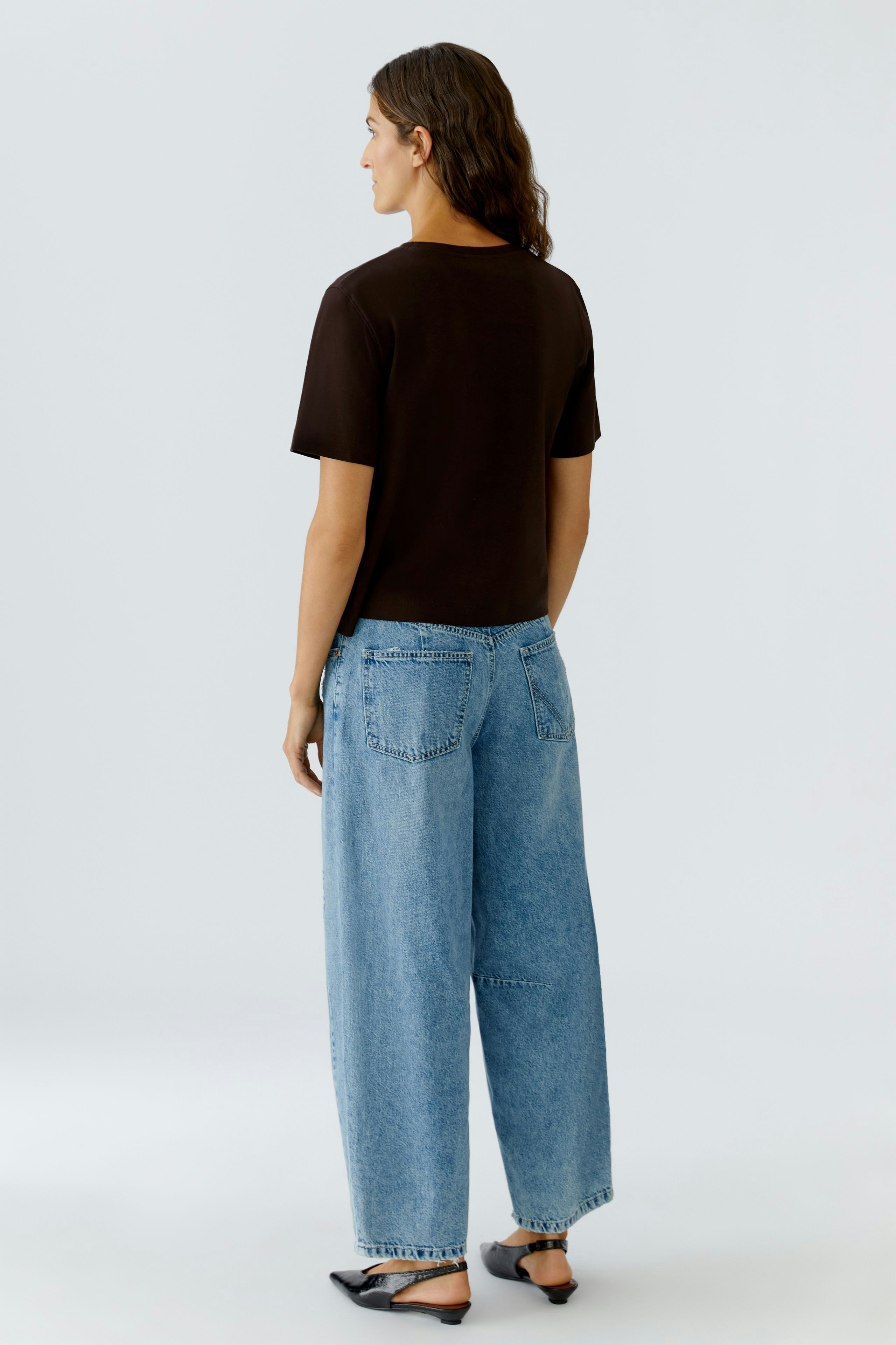 Casual women's T-shirt: A woman in a brown T-shirt paired with relaxed-fit jeans.