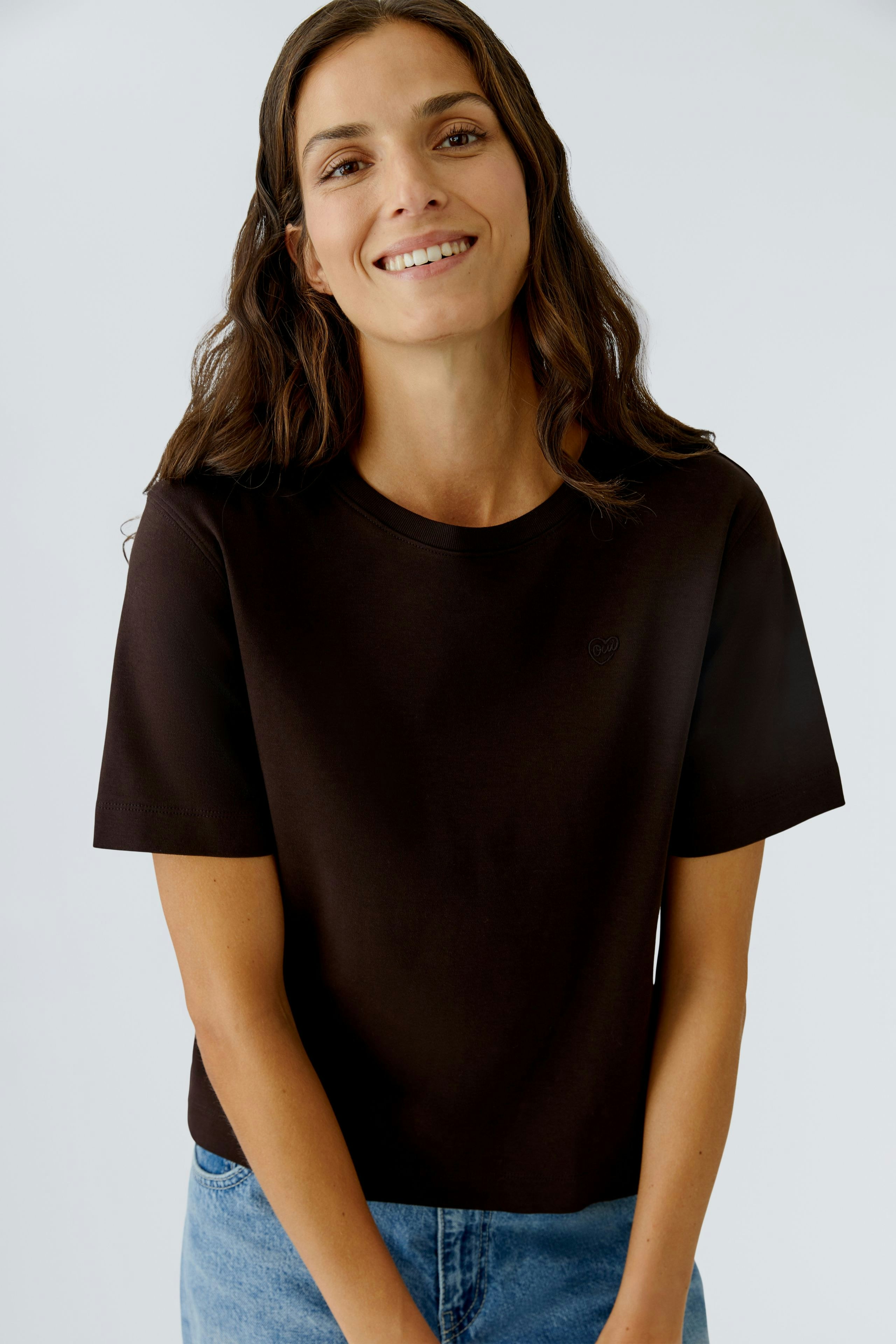 Casual women's T-shirt: Smiling woman in a black tee paired with blue jeans.