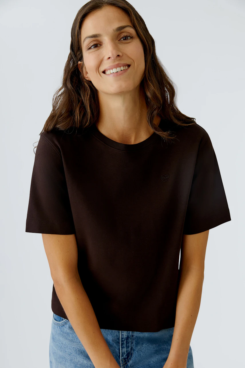 Casual women's T-shirt: Smiling woman in a black tee paired with blue jeans.