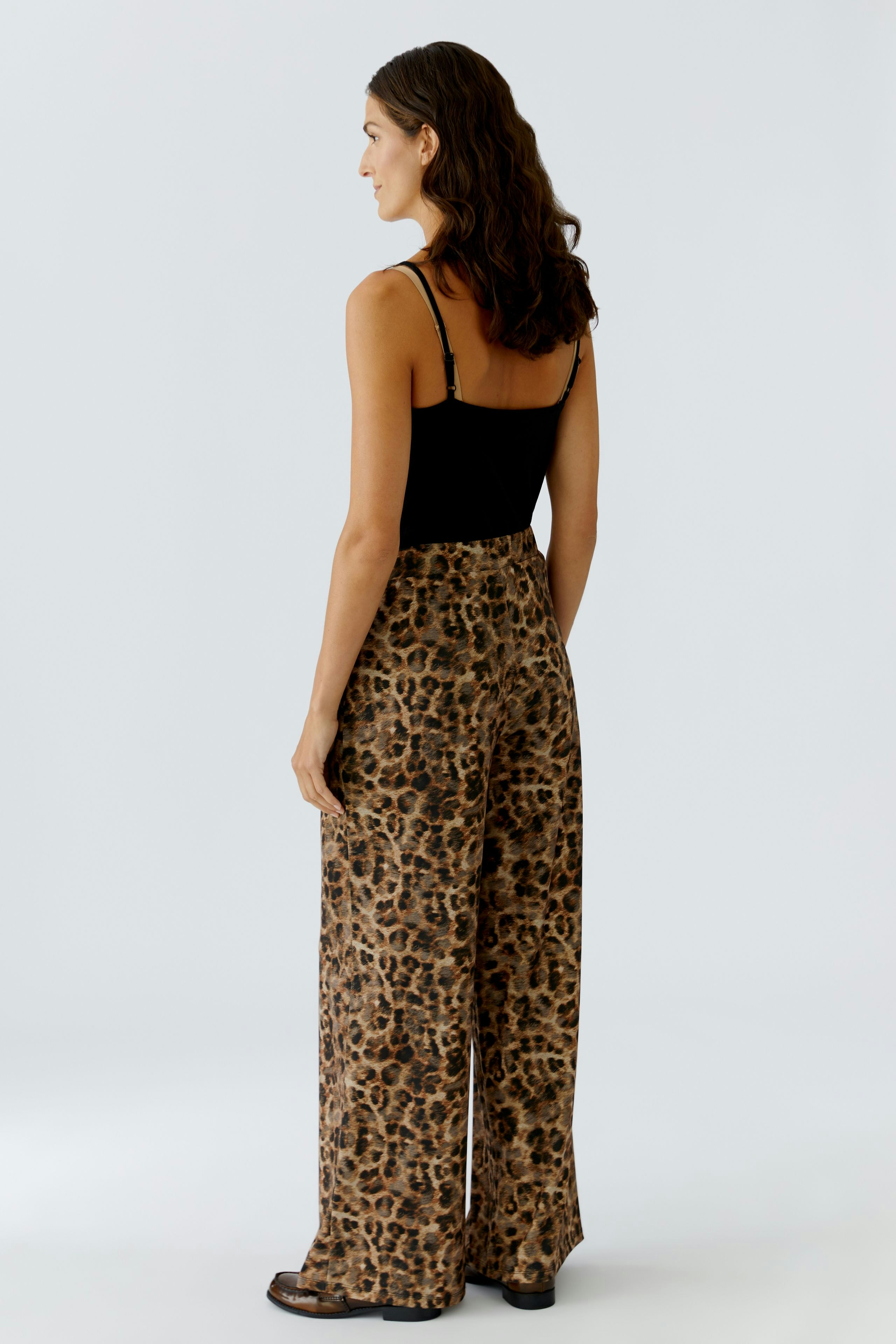 Bequeme Marlenehose: Frau trägt eine lässige Hose mit Leopardenmuster und weitem Bein.