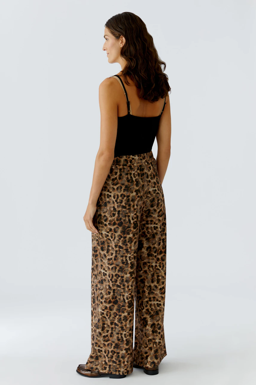 Bequeme Marlenehose: Frau trägt eine lässige Hose mit Leopardenmuster und weitem Bein.