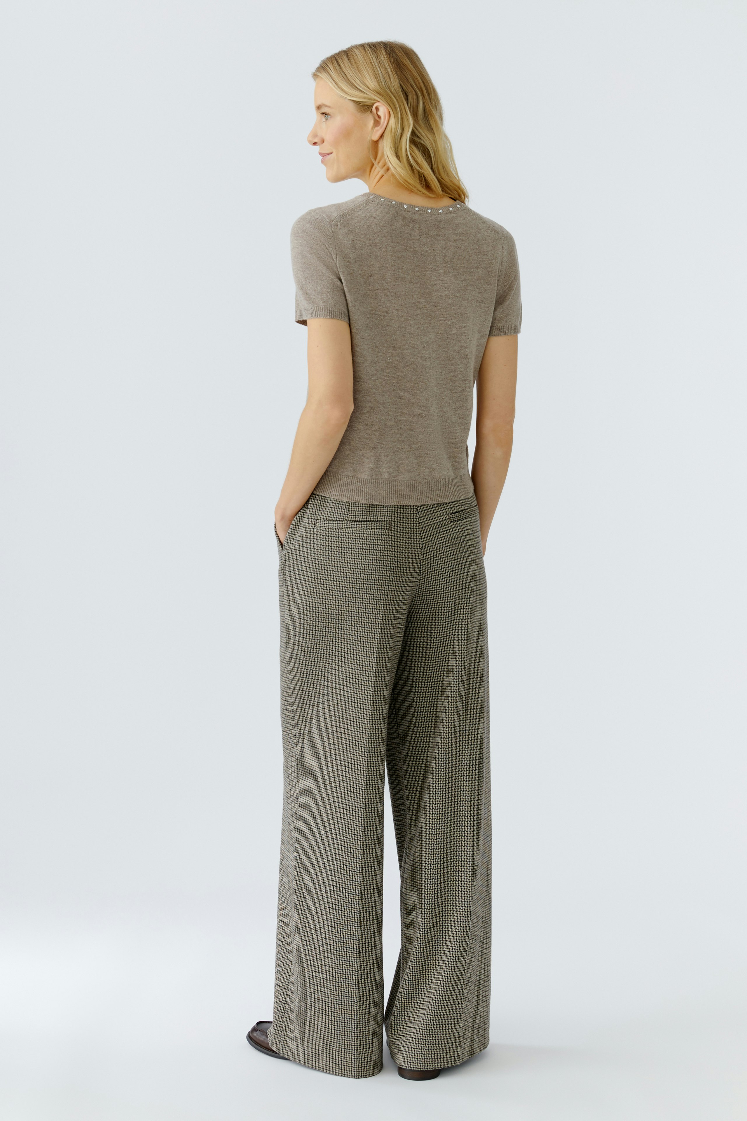 Casual women's pullover: Woman in a short-sleeve beige pullover paired with wide-leg trousers.