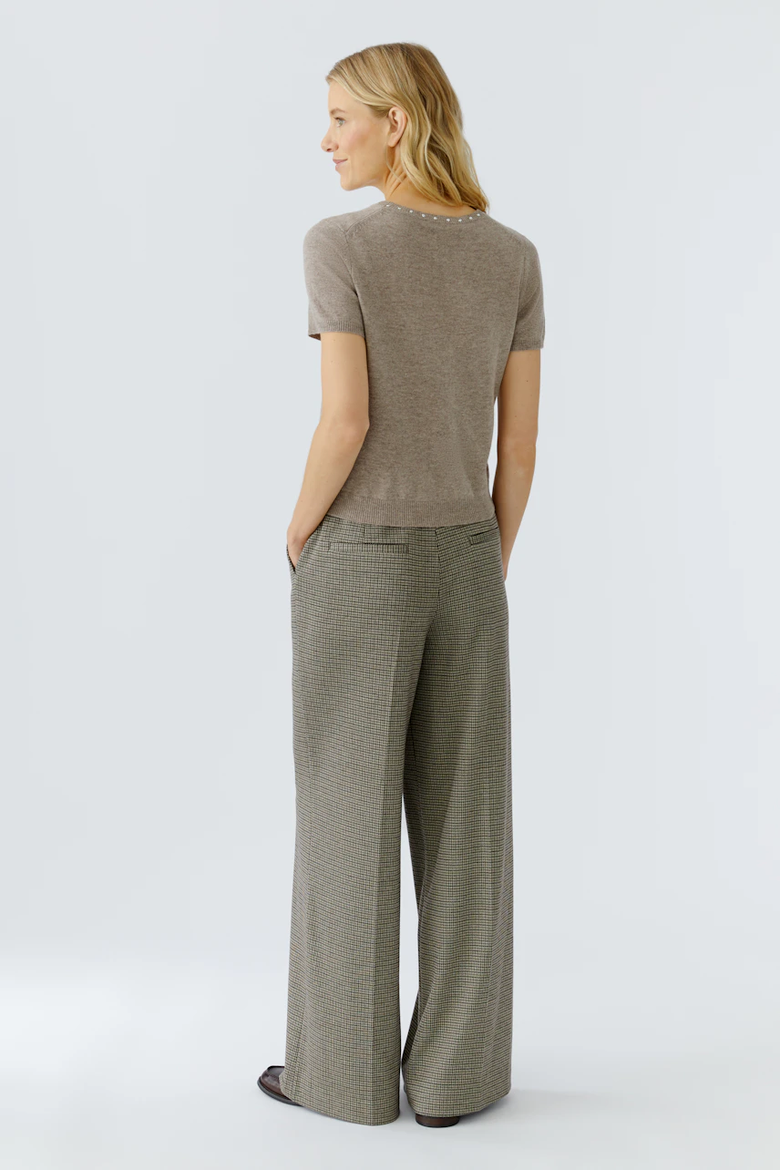 Damen-Pullover: Frau trägt einen beigen, kurzärmeligen Pullover mit lässigem Schnitt.