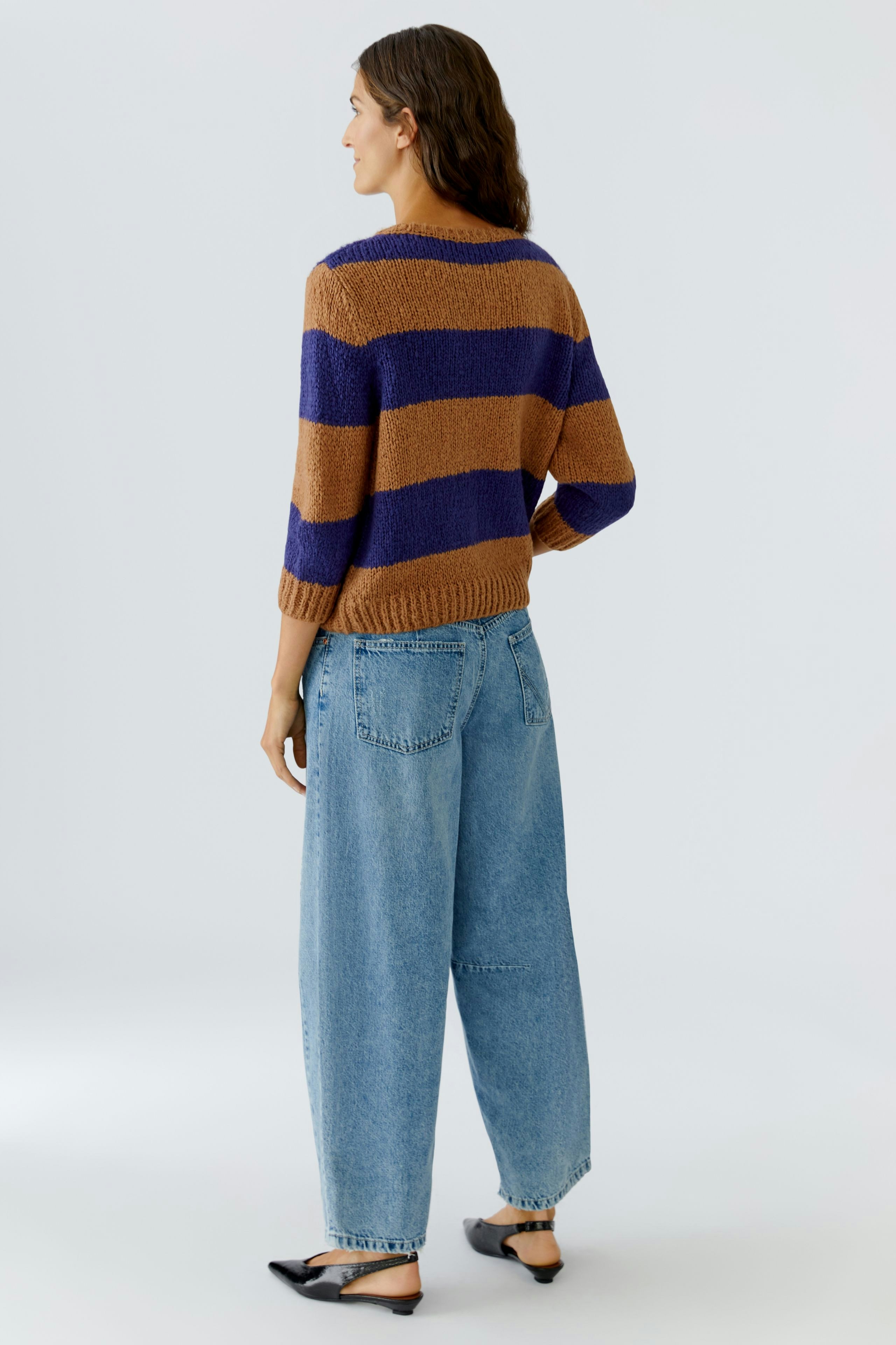 Damen-Pullover: Frau trägt einen gestreiften Pullover in Braun und Blau, kombiniert mit lässigen Jeans.
