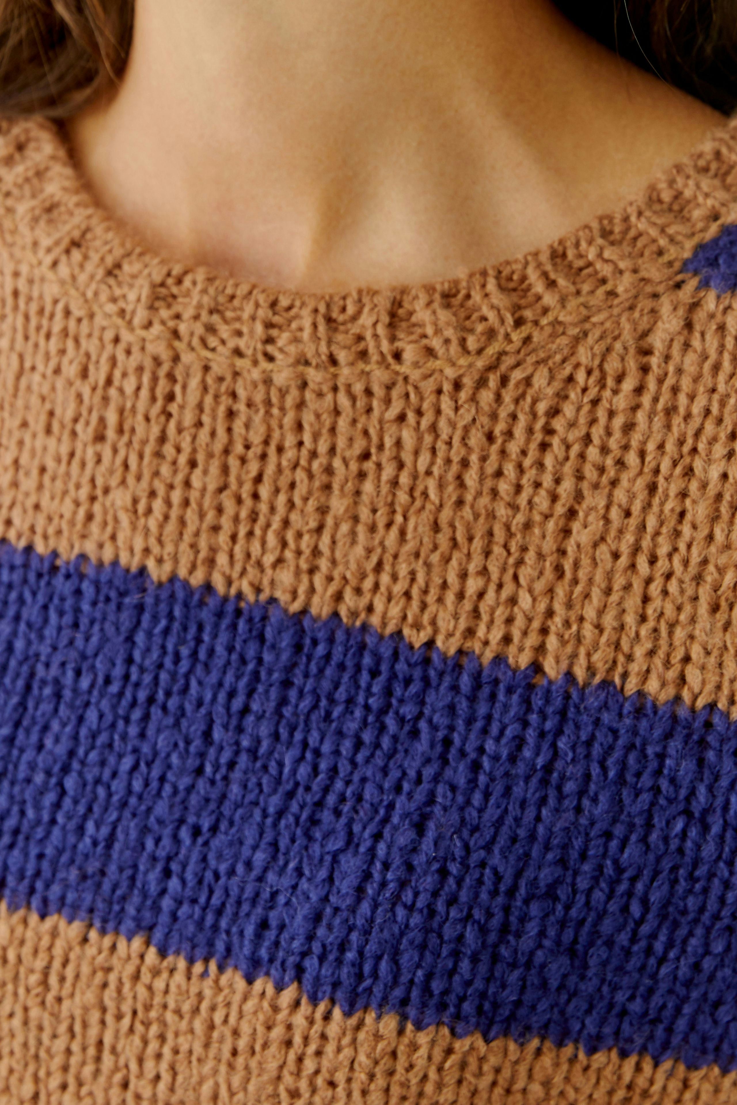 Damen-Pullover: Frau trägt einen braunen Pullover mit blauen Streifen und lässigem Rundhalsausschnitt.