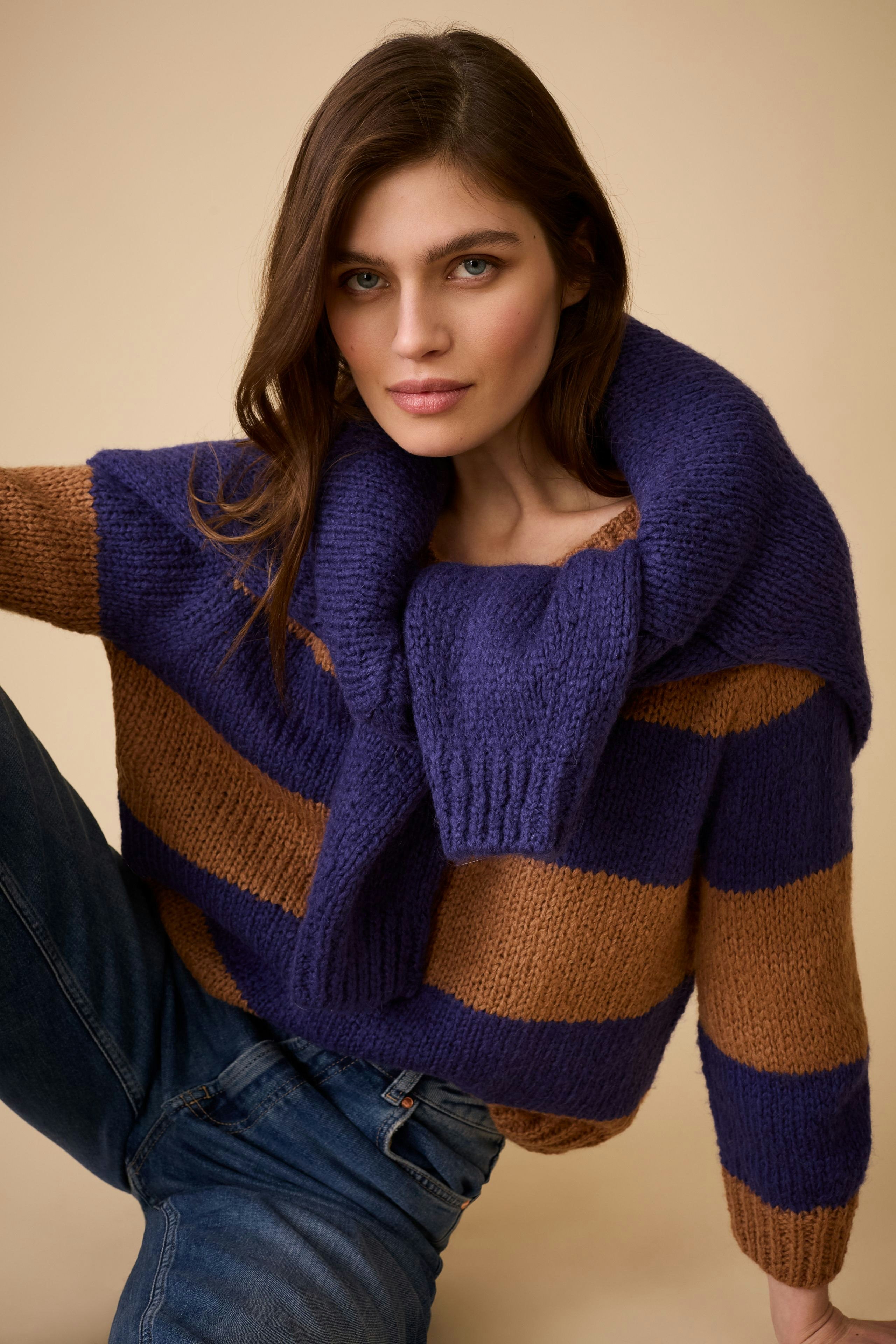 Damen-Pullover: Frau in gestreiftem Pullover mit weitem Kragen und lässiger Jeans posiert.
