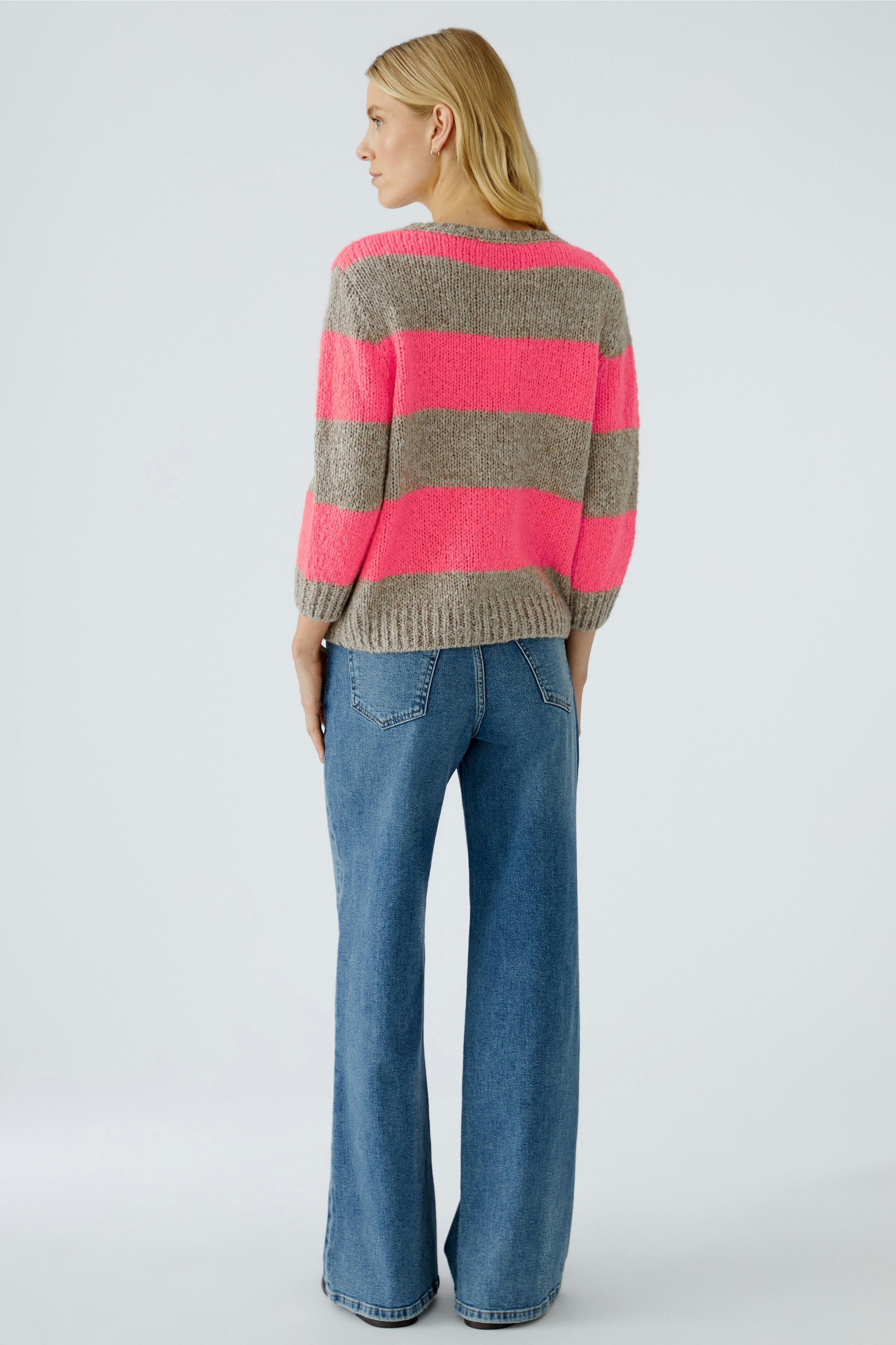 Casual women's pullover: A woman in a striped pullover with orange and gray colors, styled with wide jeans.