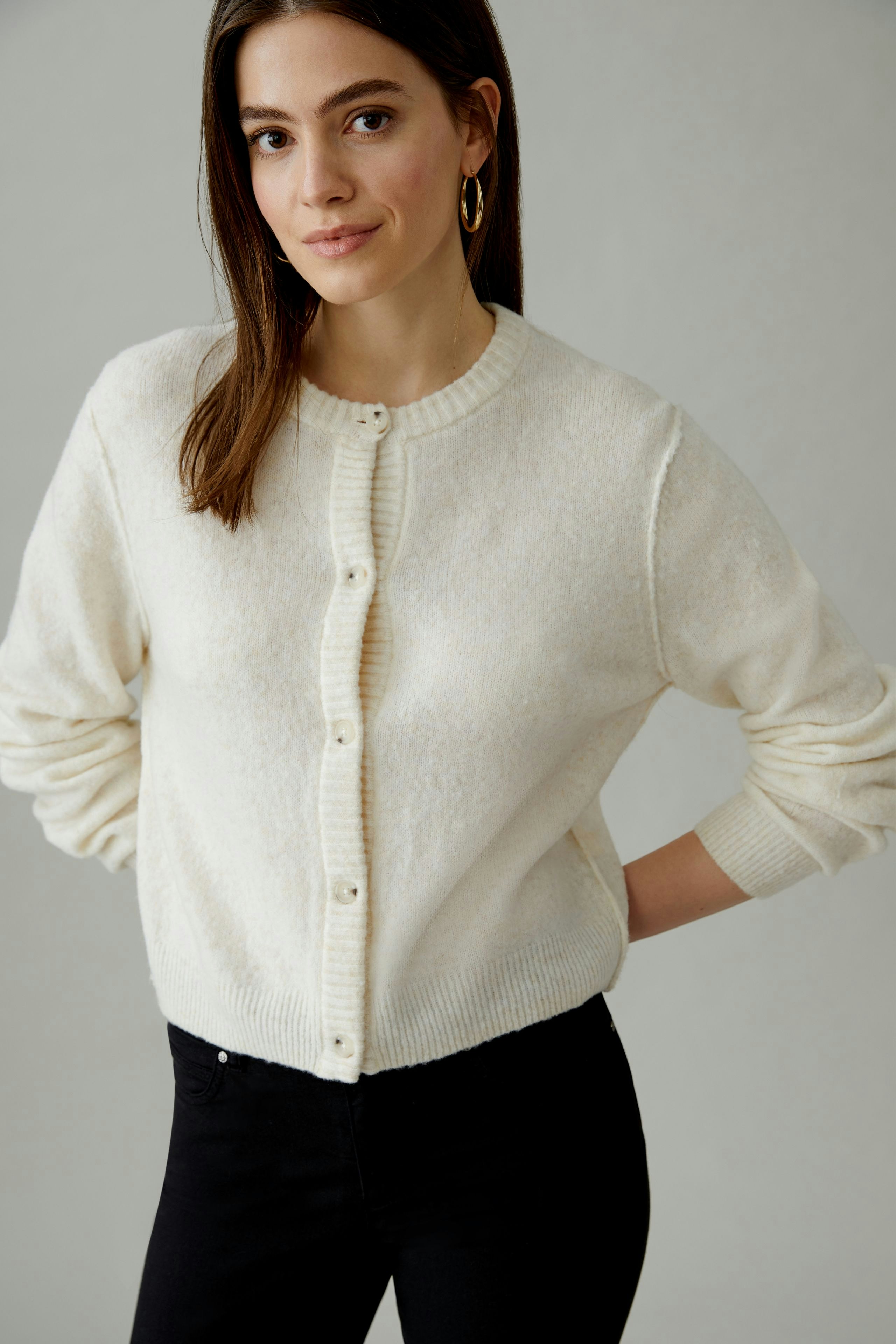 Bequeme Damen-Strickjacke: Frau in cremefarbener Jacke mit Knöpfen und lässigem Look.