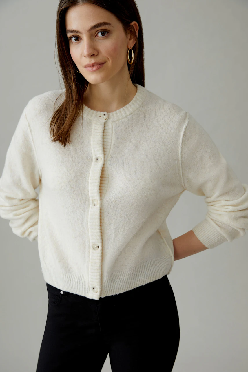 Bequeme Damen-Strickjacke: Frau in cremefarbener Jacke mit Knöpfen und lässigem Look.