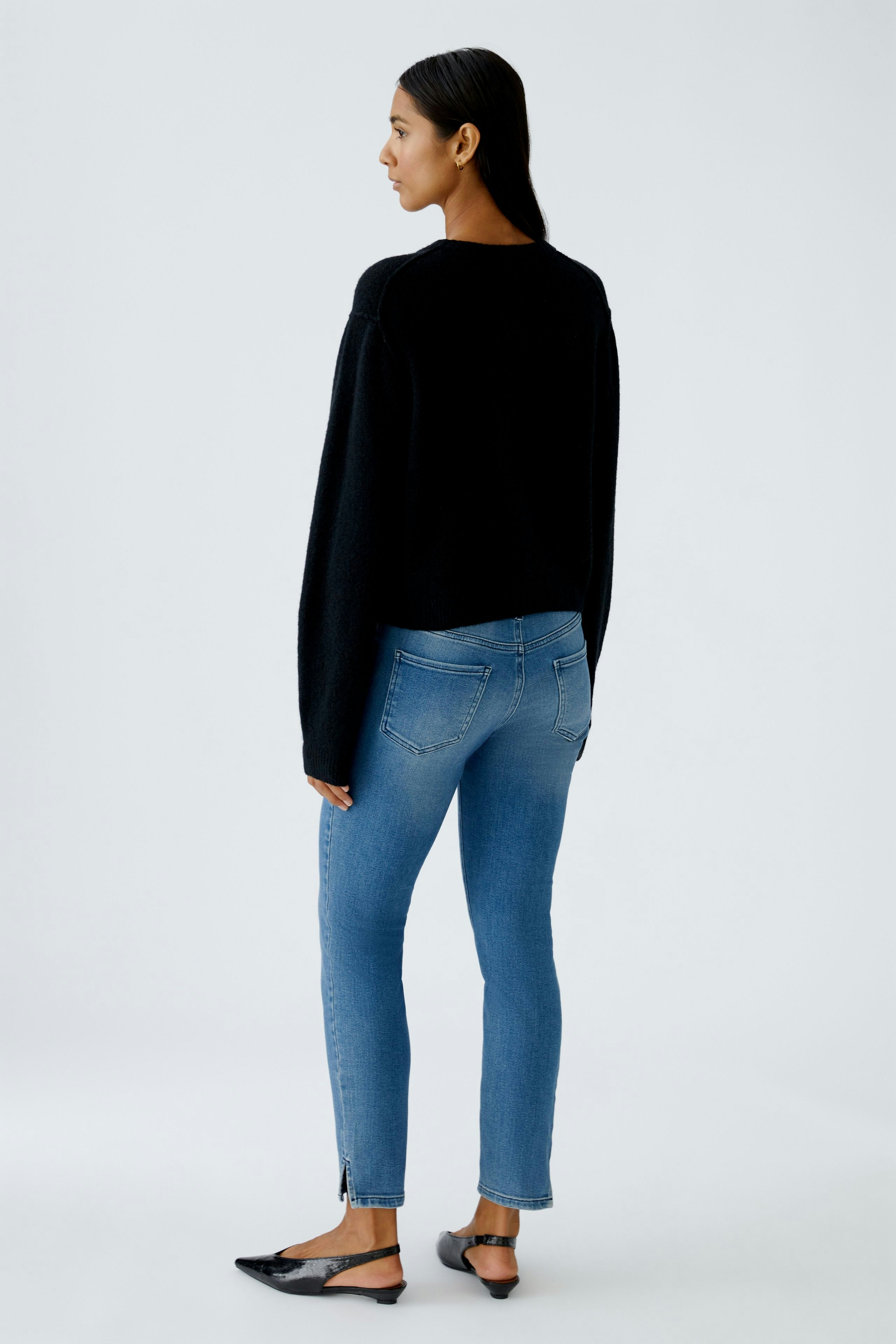 Casual women's cardigan: A woman in a black cardigan paired with blue jeans, showcasing a relaxed style.